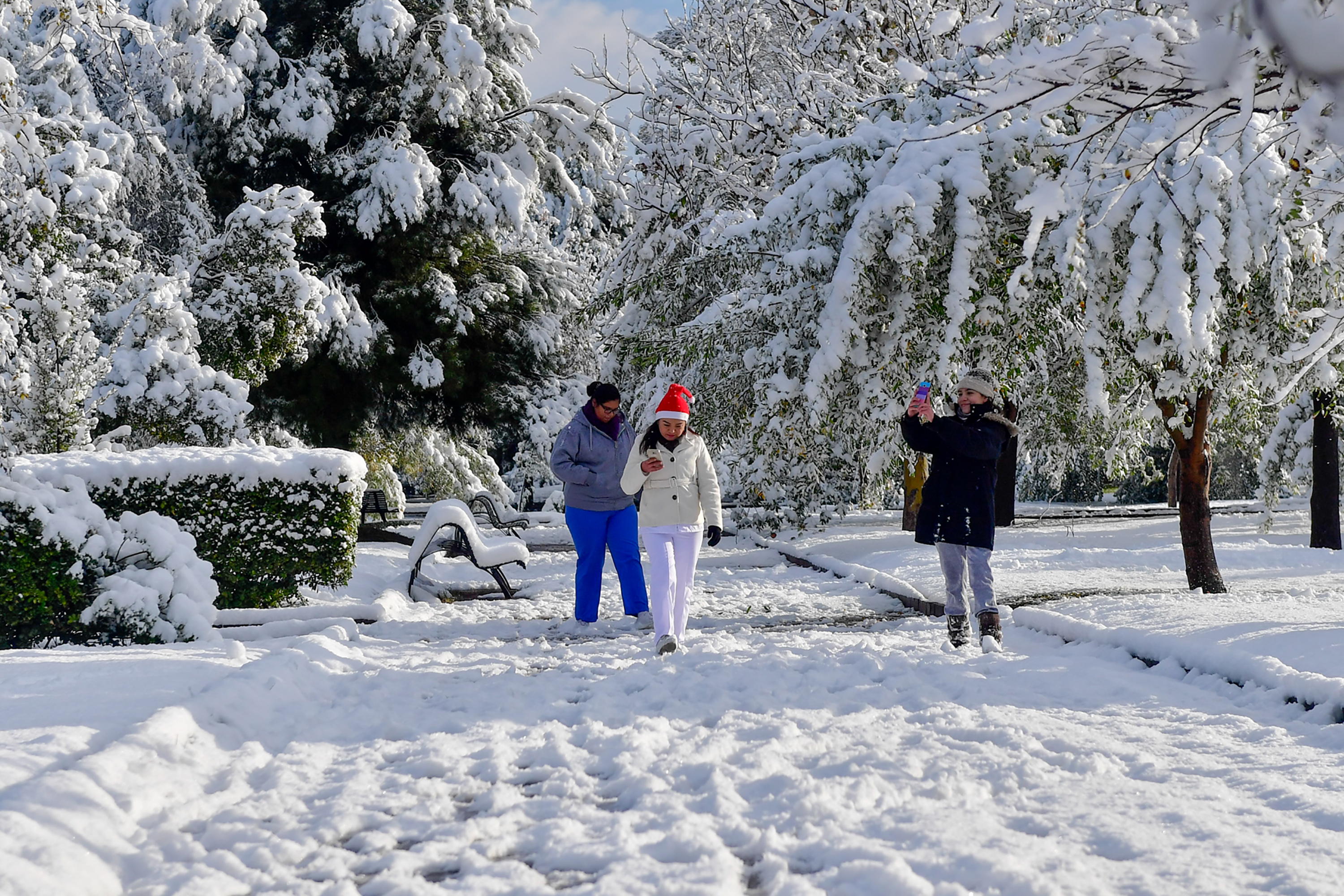 Residents walk in a park covered in snow in Monclova, Coahuila, Mexico, Dec. 8, 2017.
