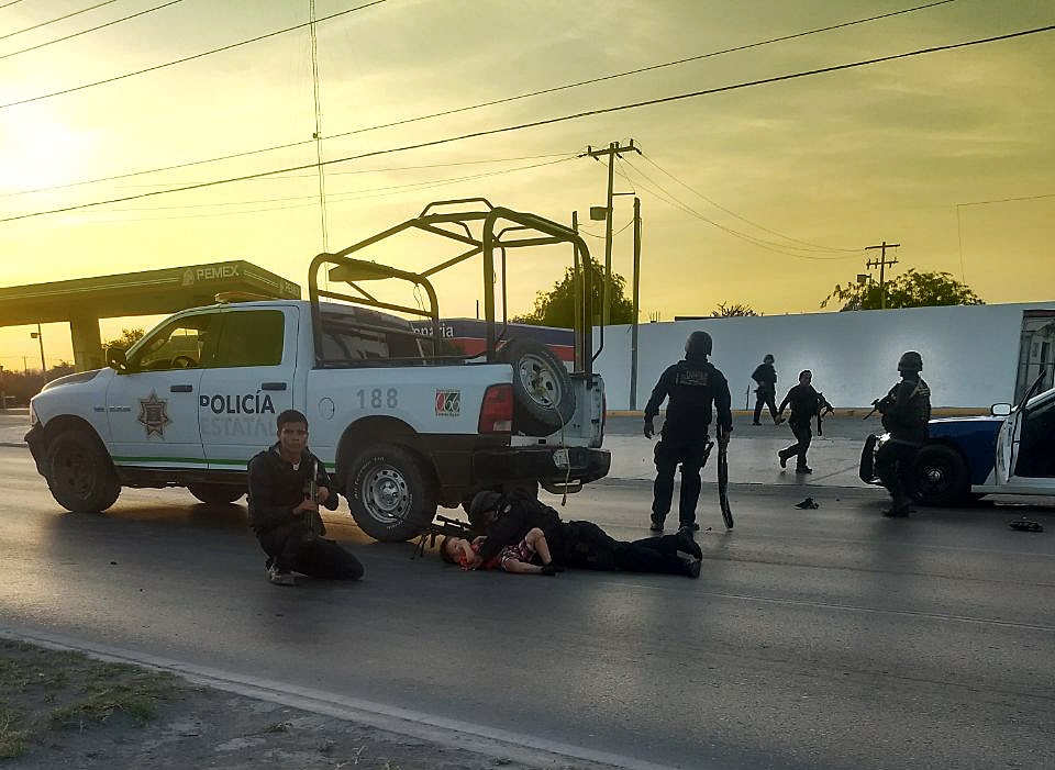 Photo provided on March 26, 2018 by the newspaper El Mañana, shows a policeman protecting a child in the area of a combat between security forces and armed groups in Nuevo Laredo, Mexico, on March 25, 2018. EPA-EFE/EL MAÑANA
