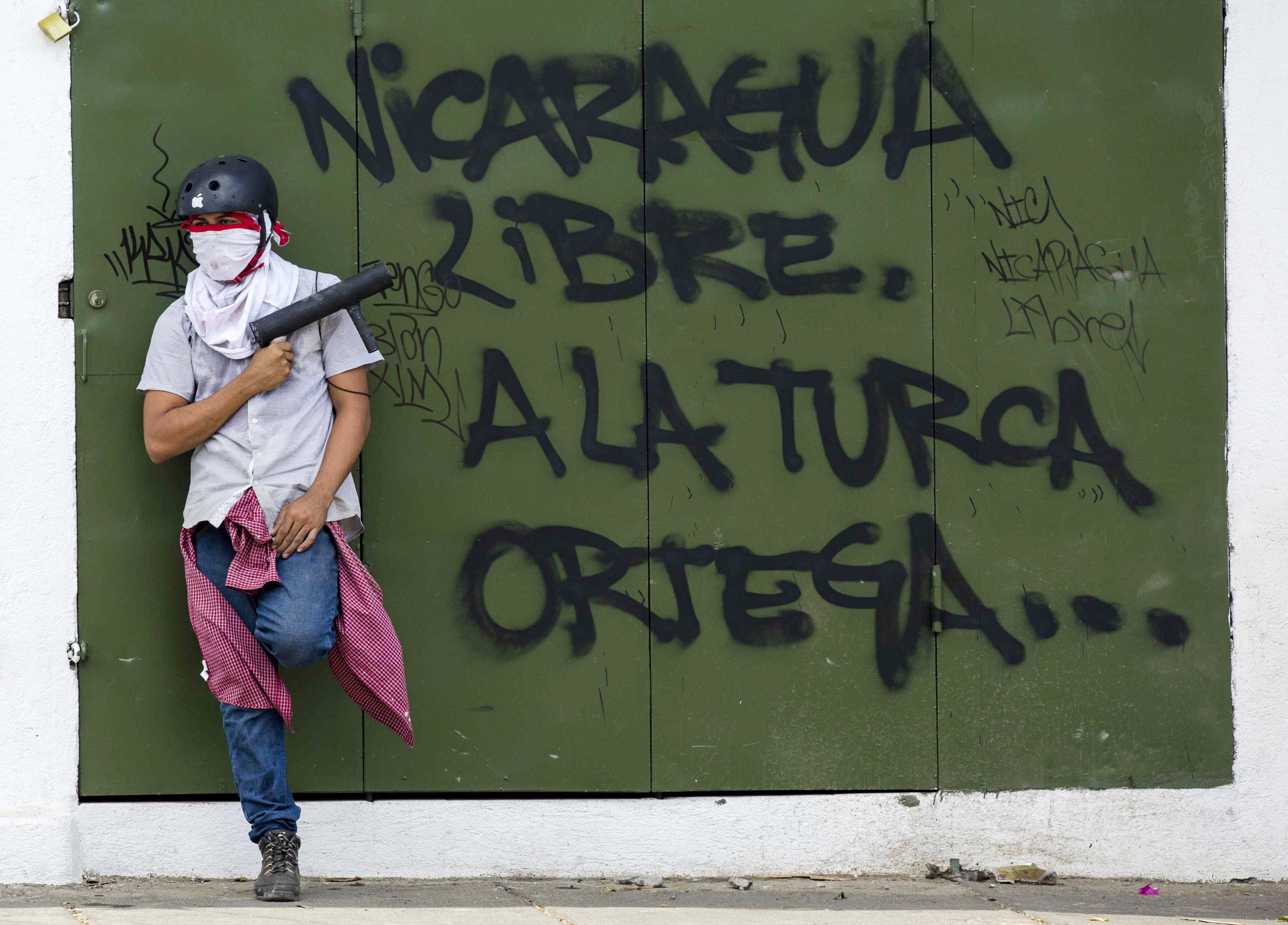 A protester holds an improvised mortar next to a graffiti repudiating the government of President Daniel Ortega in Managua, Nicaragua, April 25, 2018. EPA-EFE/Jorge Torres
