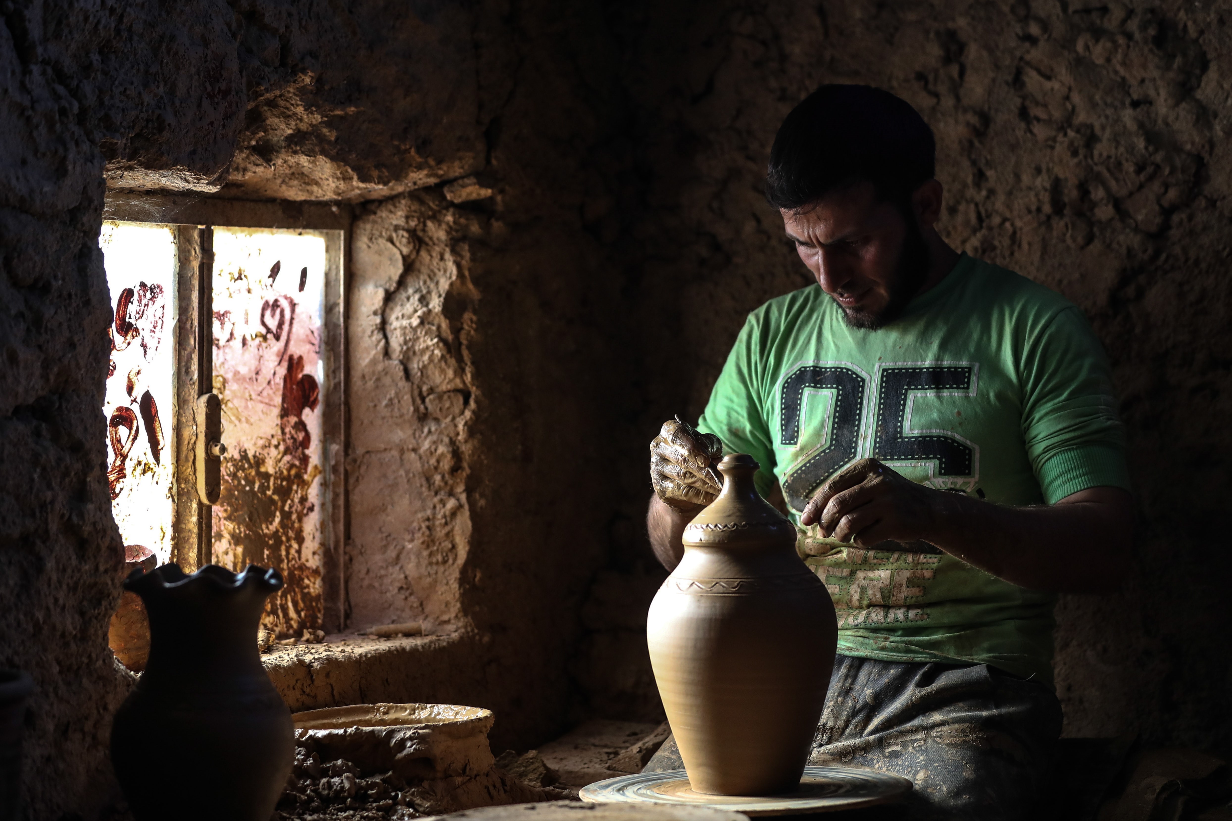 A potter works on a clay pot at a traditional pottery workshop in Armanaz, Idlib Governorate, Syria, Jul. 8, 2018. EPA-EFE/MOHAMMED BADRA
