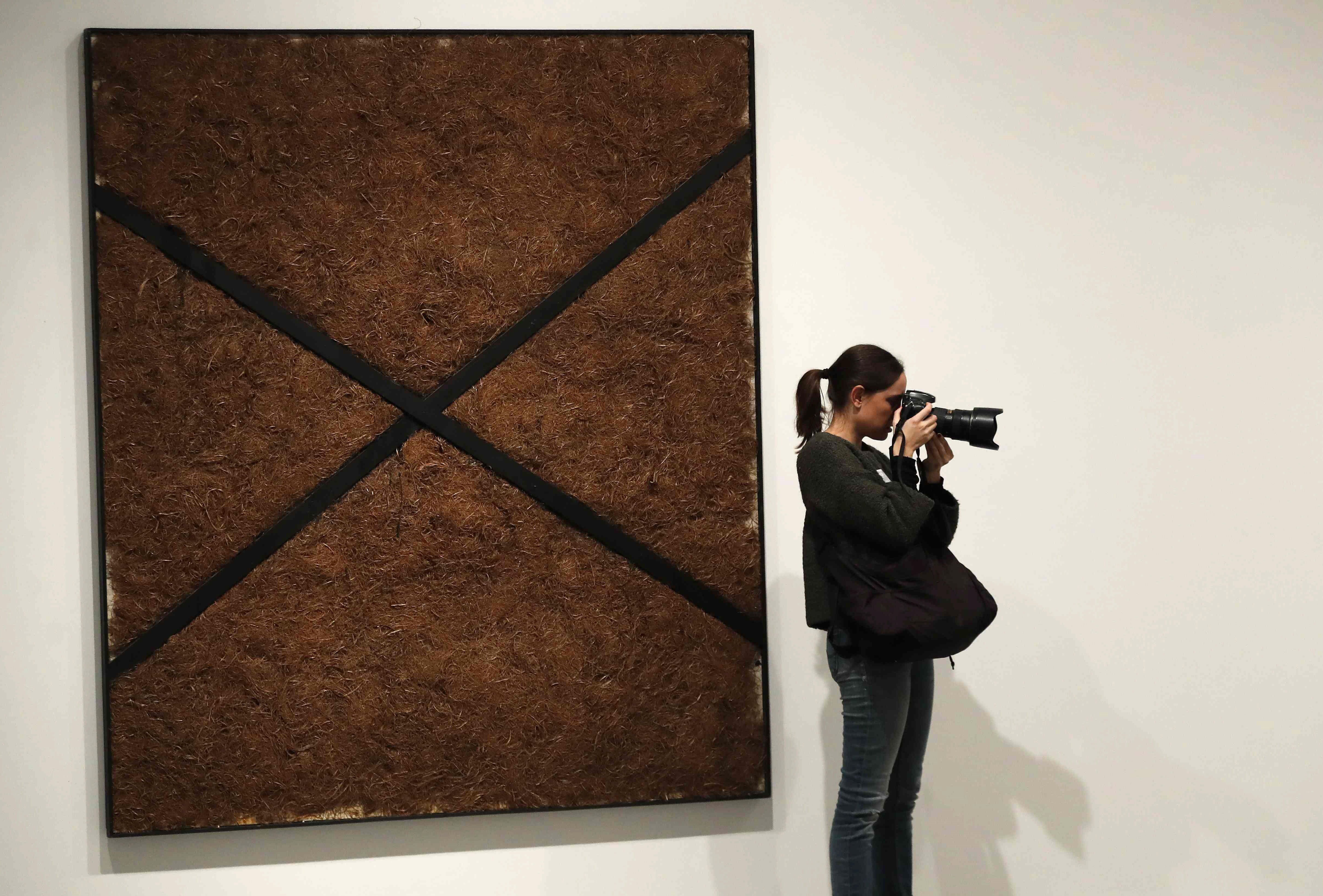 A visitor stands in front of the work 'Paja prensada a la X' during the exhibition 'Poetics of Democracy. Images and Counter-Images of the Transition' at the Reina Sofia Museum in Madrid, Spain, Dec. 3, 2018. EPA-EFE/Chema Moya