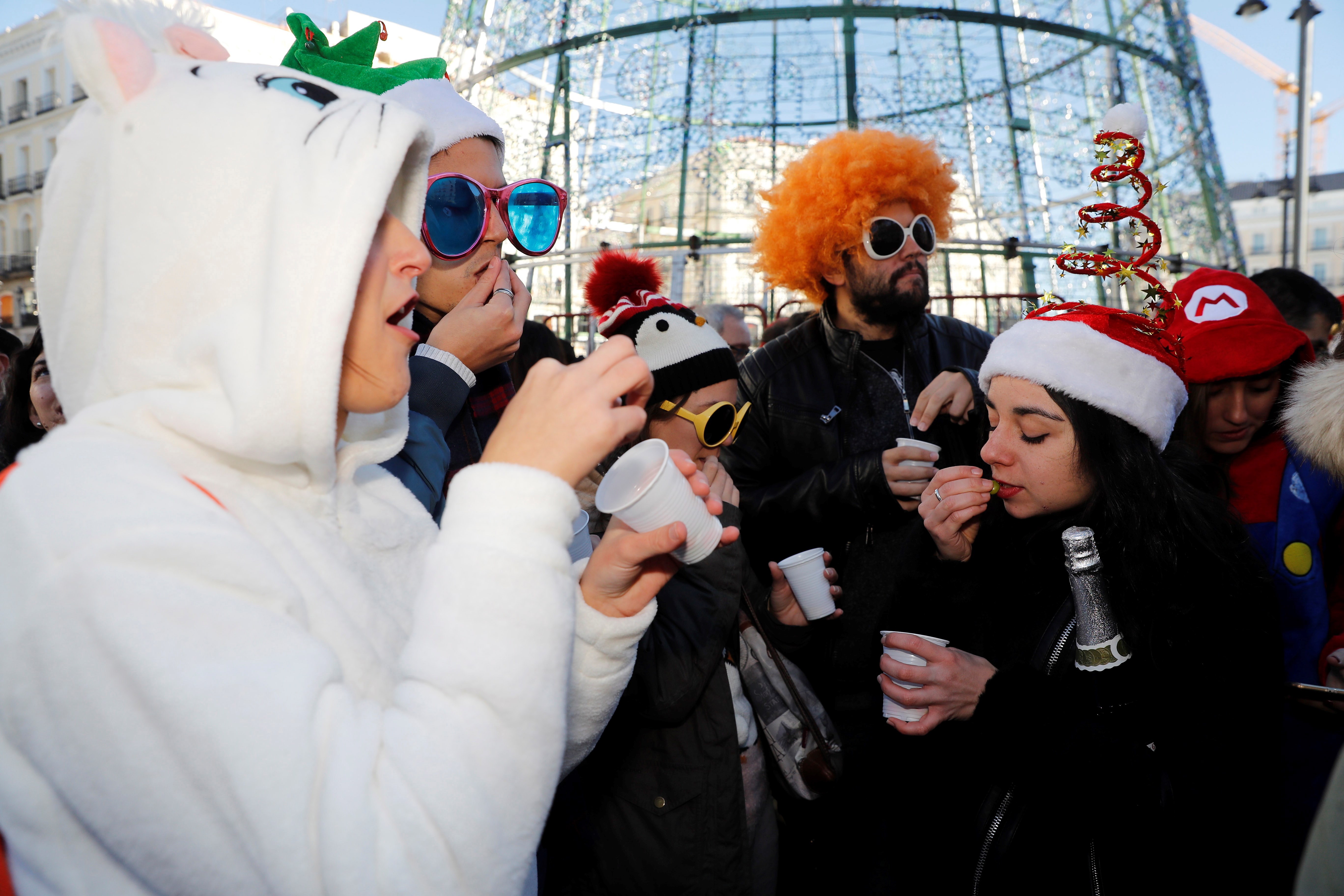 People eat grapes to the sound of twelve strokes at noon in front of the clock at Puerta del Sol square, downtown Madrid, Spain during the last 'rehearsal' of New Year's Eve tradition, Dec. 31, 2018. EFE
