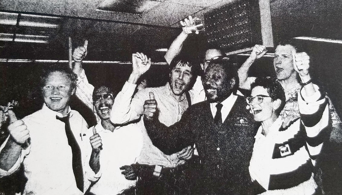 El 13 de abril, la sala de redacción del Oakland Tribune, liderada por el presidente Bob Maynard (centro, con chaqueta y corbata), celebraron después de ganar el  premio Pulizter por su cobertura del terremoto de Loma Prieta. Foto cortesía del Maynard Institute. Foto: Cortesía del instituto Maynard. 