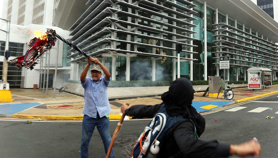 Un manifestante ondea una bandera quemada ,en San Juan, Puerto Rico, durante el paro general contra los recortes, que coincide con el Primero de Mayo, Día Internacional del Trabajador. EFE
