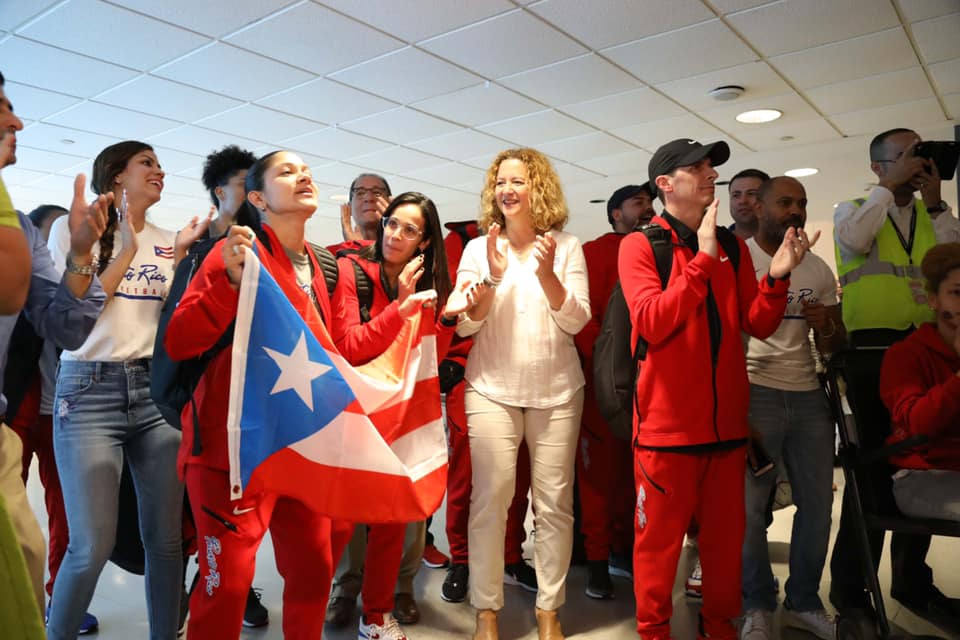 Puerto Rican women's basketball team captain Pamela Rosado dances with the Puerto Rican flag after returning home from Olympic qualifiers in France. The Puerto Rico women's basketball team qualified for its first Olympic games ever. Photo: Federación de Baloncesto de Puerto Rico (Facebook).