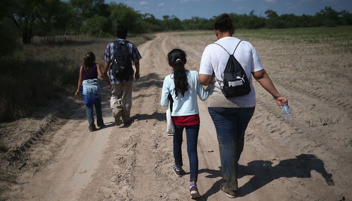 Families of Central American immigrants walk through the countryside after crossing from Mexico to the United States to seek asylum on April 14, 2016 in Rome, Texas. Photographer: John Moore / Getty Images