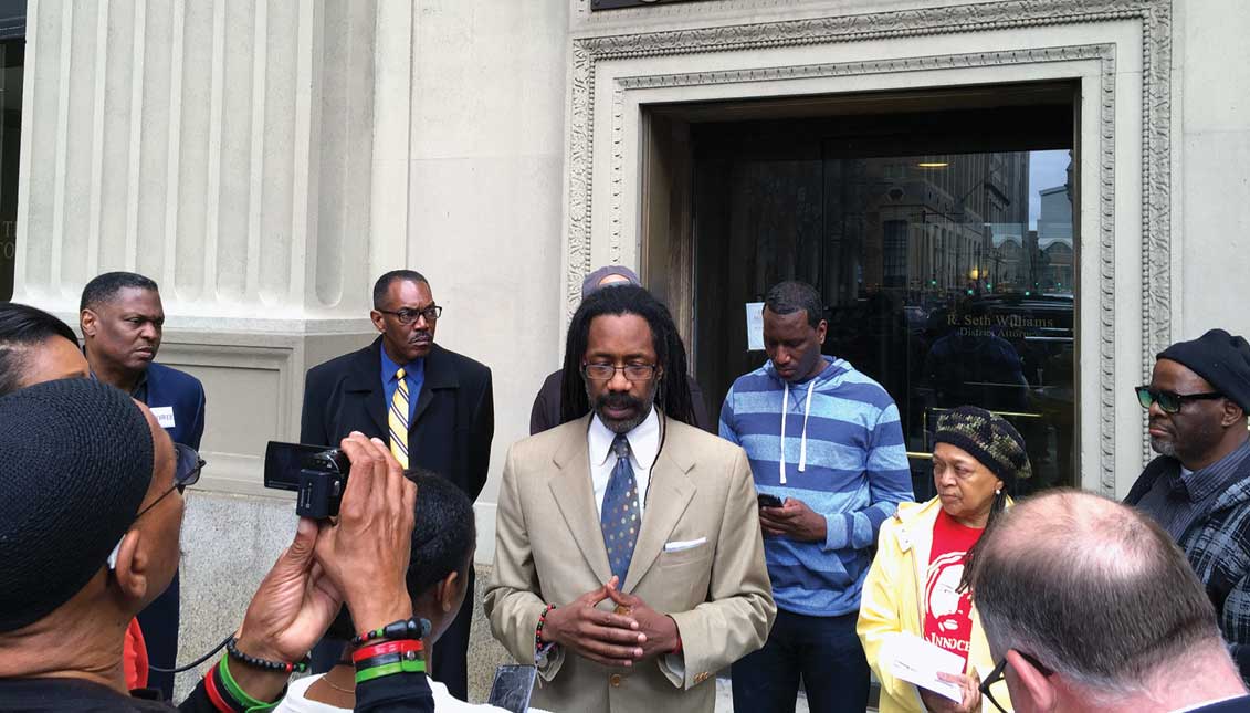 Attorney Michael Coard speaks at April 2017 protest demanding the resignation of DA Seth Williams following Williams' federal corruption indictment. Philadelphia NAACP president Rodney Muhammad (yellow tie) joined others including Mumia Abu-Jamal activist Pam Africa (red tee shirt) and Greg Brinkley (far right) whose investigation ultimately freed a teen in the 911-dialing-dog false arrest. LBWPhoto.
