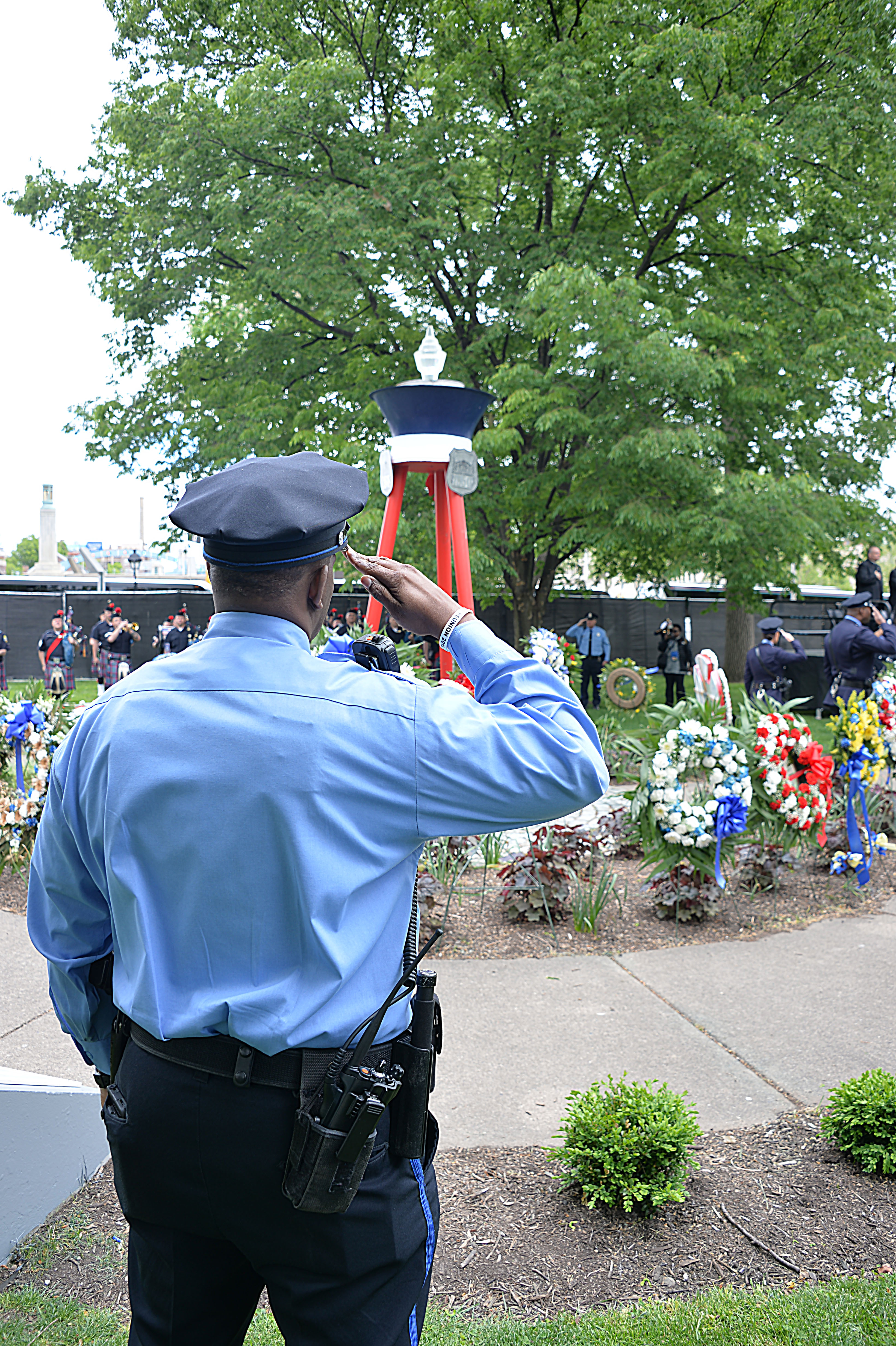 A Philadelphia police officer salutes during the playing of taps at the Living Flame Memorial Service. Photo: Peter Fitzpatrick/AL DIA News