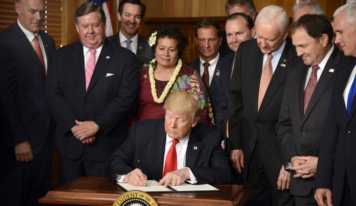 El presidente Donald J. Trump (c), firma el decreto en el que se ordena revisar la designación de decenas de áreas protegidas conocidas como "monumentos nacionales" en los últimos 20 años. EFE/Mike Theiler
