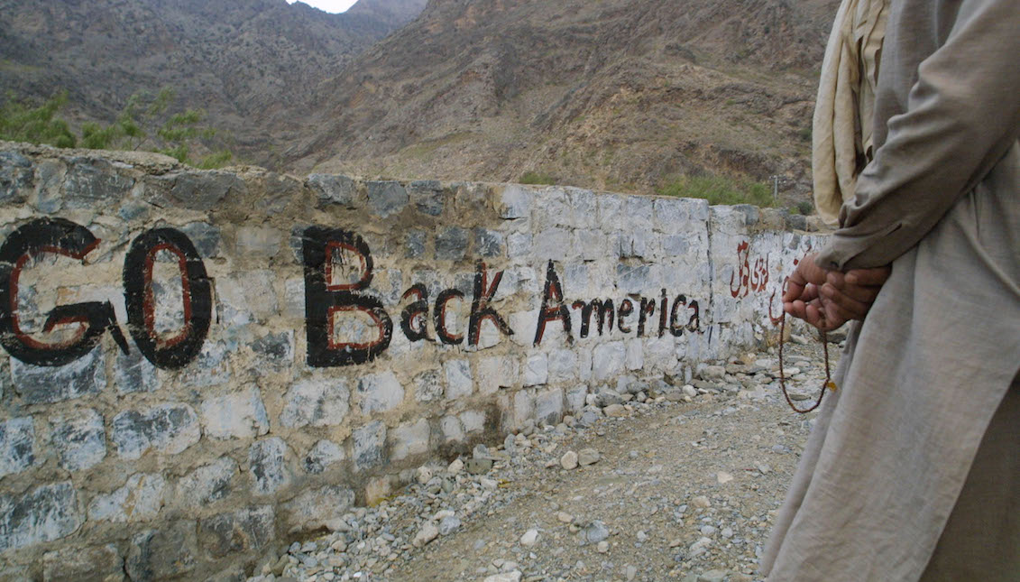 A man holds prayer beads near a stone wall that reads "Go Back America" September 20, 2001, near the Khyber Pass on the Pakistani border with Afghanistan. (Photo by Paula Bronstein/Getty Images)