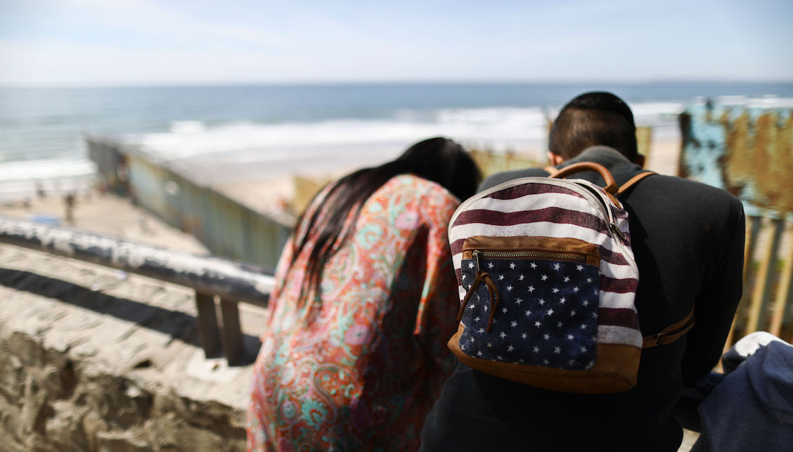 TIJUANA, MEXICO - MARCH 31: A man wears a backpack decorated as an American flag above the border barrier, at the U.S.-Mexico barrier on the beach, on March 31, 2019 in Tijuana, Mexico. U.S. President Donald Trump told reporters Friday “there's a very good likelihood” that he will close the U.S. southern border next week. (Photo by Mario Tama/Getty Images)