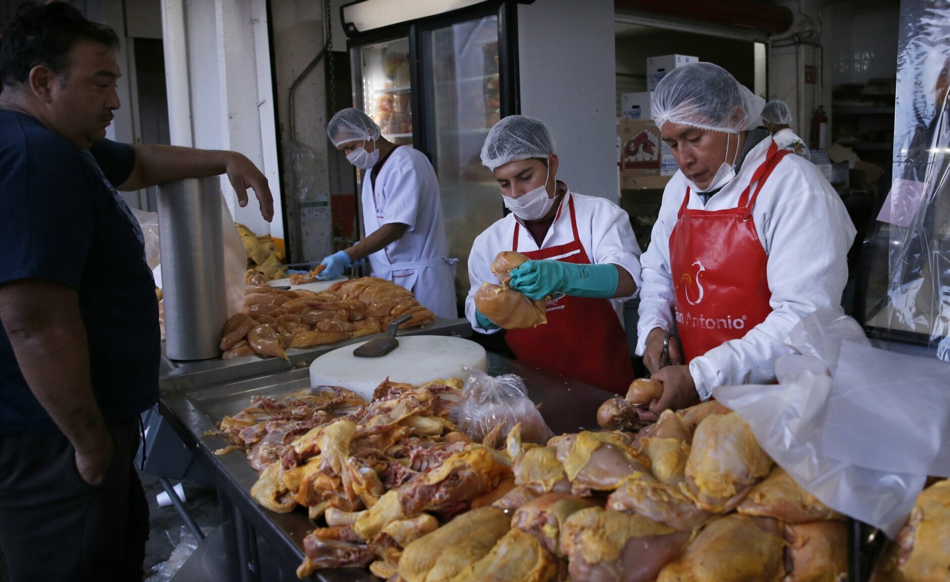 A client waits for his chicken from workers wearing face masks as a precautionary measure amid the spread of coronavirus at the Centro de Abastos in Mexico City. Photo: Marco Ugarte/AP.