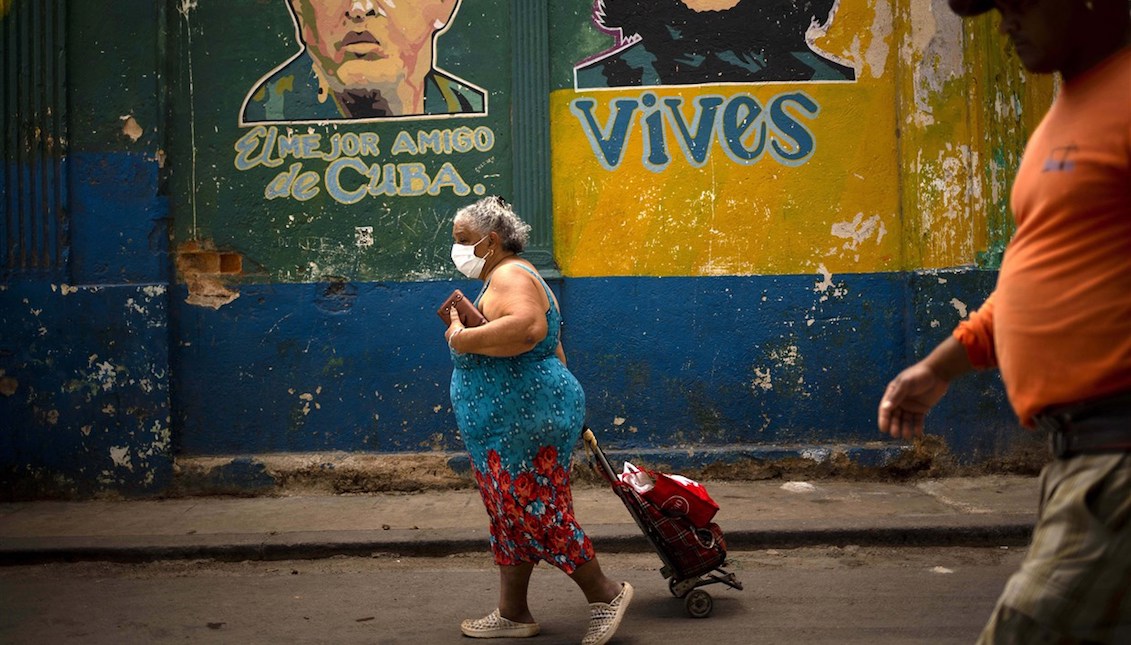 A woman, wearing a protective mask as a precaution against the spread of the new coronavirus, pulls along her shopping caddy as she walks to the market in Havana on March 24, 2020. Ramon Espinosa / AP