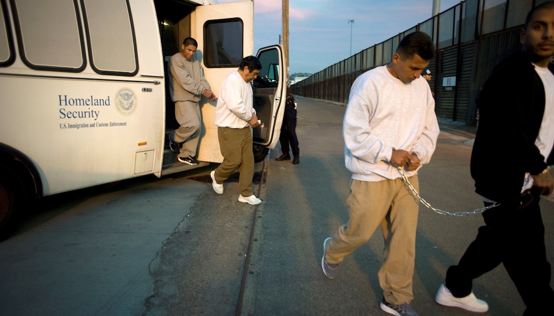 Stock photo showing several men being taken from a bus to a deportation gate on the US-Mexico border in 2015. Photo by David Maung.