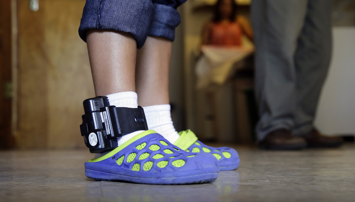 An adult immigrant from El Salvador who entered the country illegally uses an ankle monitor on July 27 at a shelter in San Antonio. Eric Gay/AP