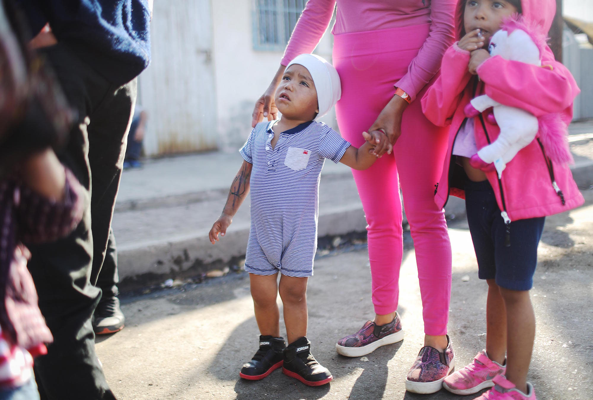  Honduran children Eduardo, 2, and Richi, 5, stand with their mother outside a temporary migrant shelter set up near the U.S.-Mexico border on November 20, 2018 in Tijuana, Mexico. Photo: Mario Tama/Getty Images.