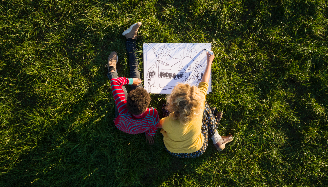 Teenage boy and girl on grass experimenting and drawing sustainable energy solutions, overhead view. Photo: Mischa Keijser Getty Images. 