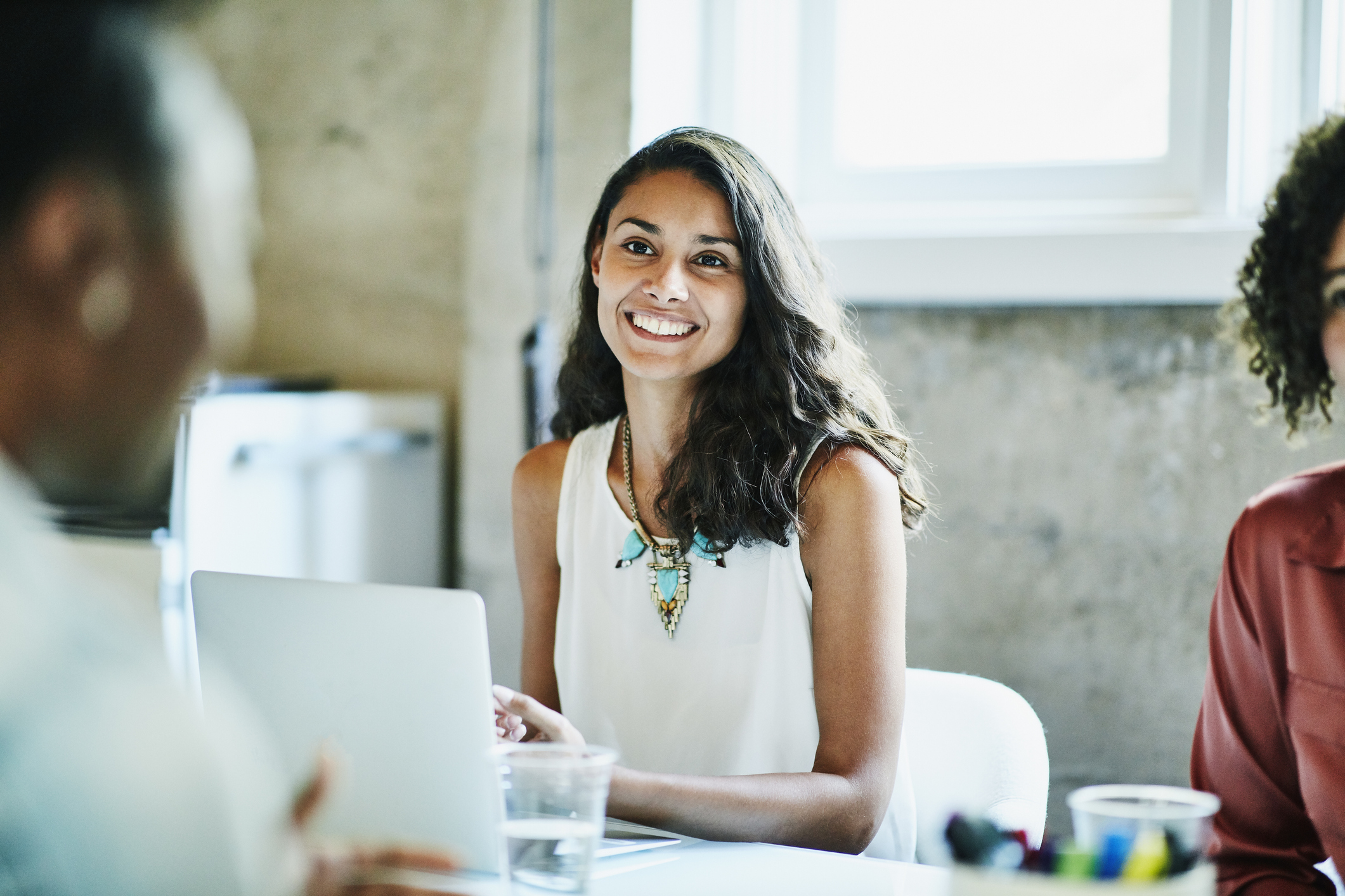 Smiling businesswoman in discussion with colleagues during meeting in office conference room - Getty Images stock photo