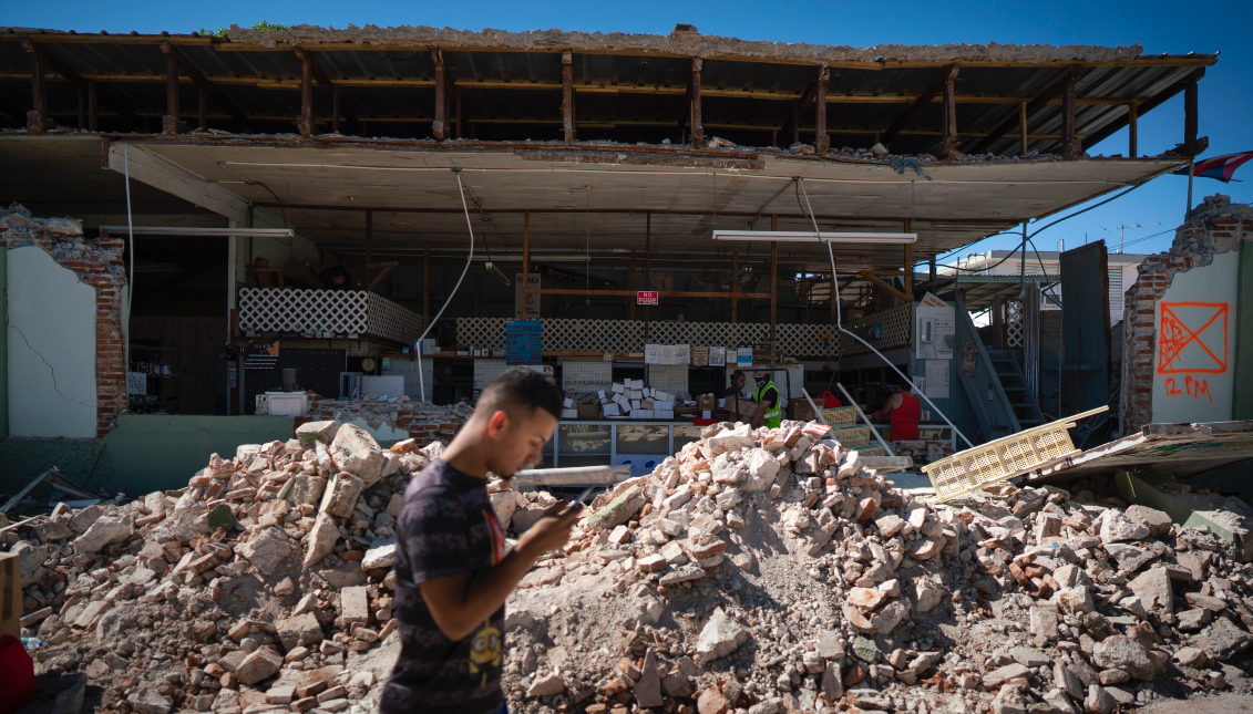 GUANICA, PUERTO RICO - JANUARY 7: A man walks past a destroyed store after a 6.4 earthquake hit just south of the island. (Photo by Eric Rojas/Getty Images)