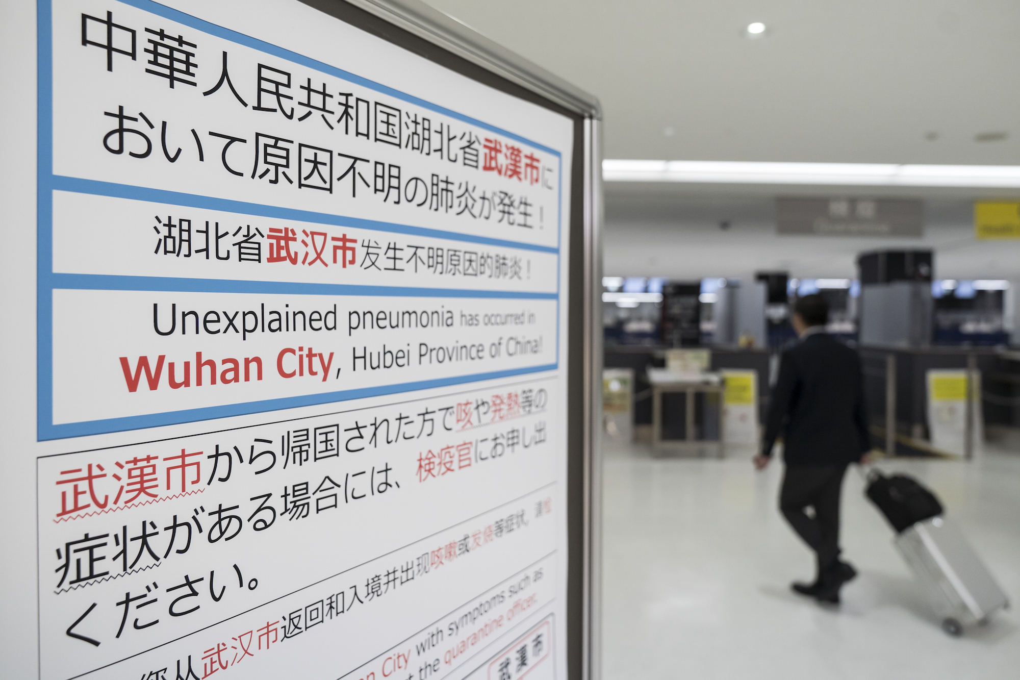 A passenger walks past a notice for passengers from Wuhan, China displayed near a quarantine station at Narita airport on January 17, 2020 in Narita, Japan. Photo: Tomohiro Ohsumi/Getty Images.