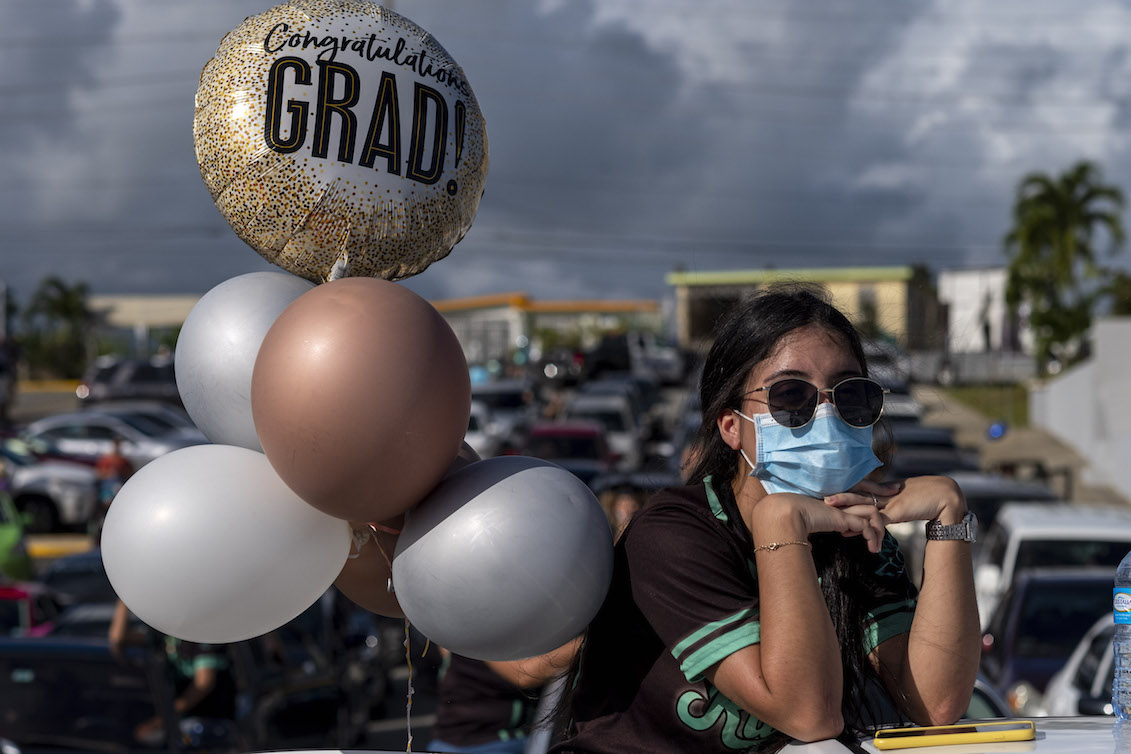 Un estudiante graduado de la Preparatoria Ramon Power Y Giralt usa una mascarilla durante una graduación simbólica desde sus autos para mantener la distancia social en un estacionamiento en Las Piedras, Puerto Rico, el 13 de mayo de 2020. Foto: Ricardo Arduengo / AFP vía Getty Imágenes.