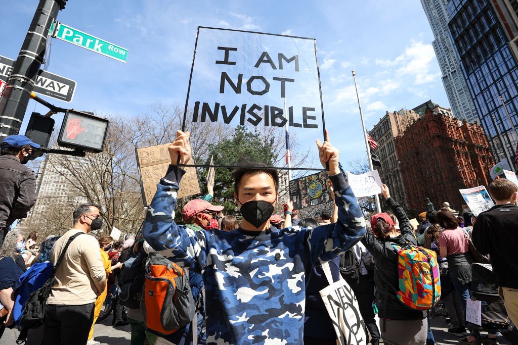 Asian-American man holding poster that reads "I am not invisible." Photo: Anadolu Agency/Getty Images