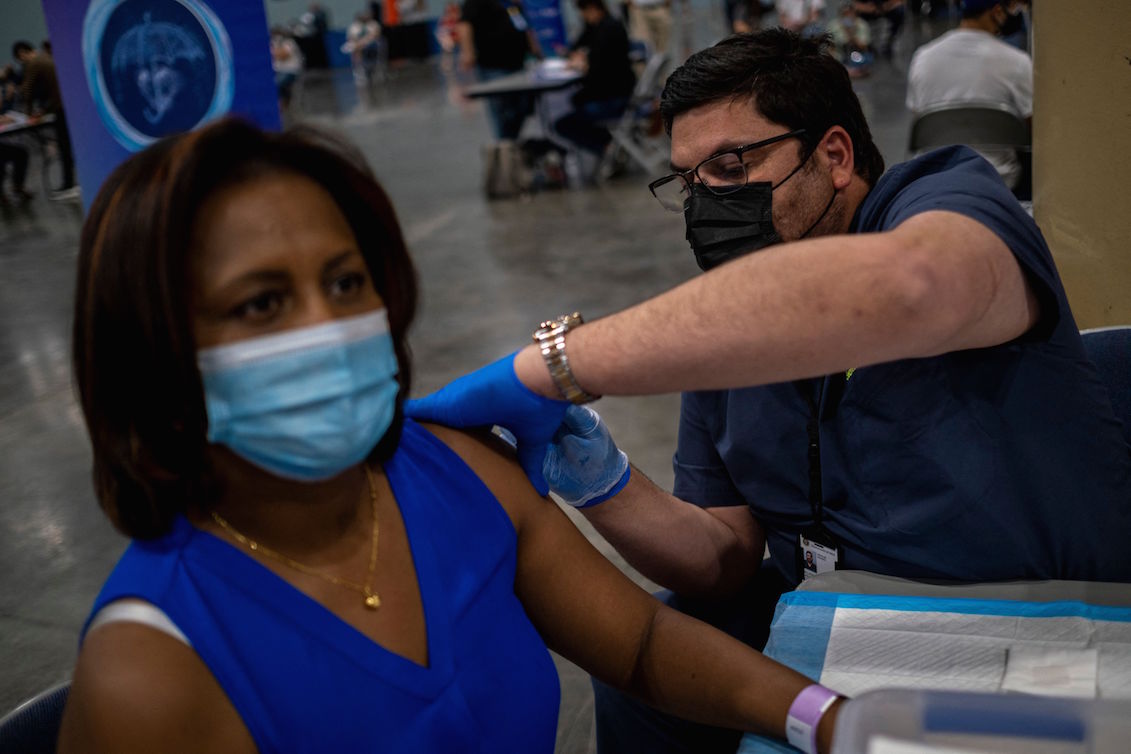 Puerto Rico's Health Department Secretary, Dr. Carlos Mellado (L) inoculates a woman with the Johnson and Johnson Covid-19 vaccine at the Puerto Rico Convention Center in San Juan, Puerto Rico on March 31, 2021. Photo: Ricardo Arduengo/AFP via Getty Images