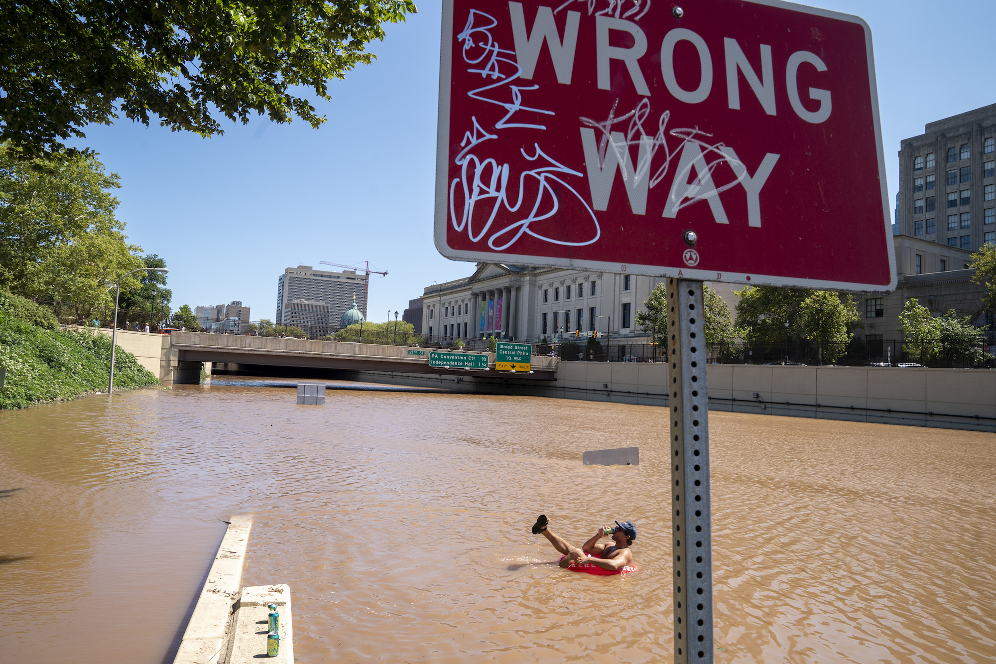 Austin Ferdock drinks a beer while floating in floodwater that continues to rise over the submerged Vine Street Expressway, Interstate 676, following a huge storm caused by the remnants of Hurricane Ida on September 2, 2021 in Philadelphia, Pennsylvania. Photo: Jessica Kourkounis/Getty Images