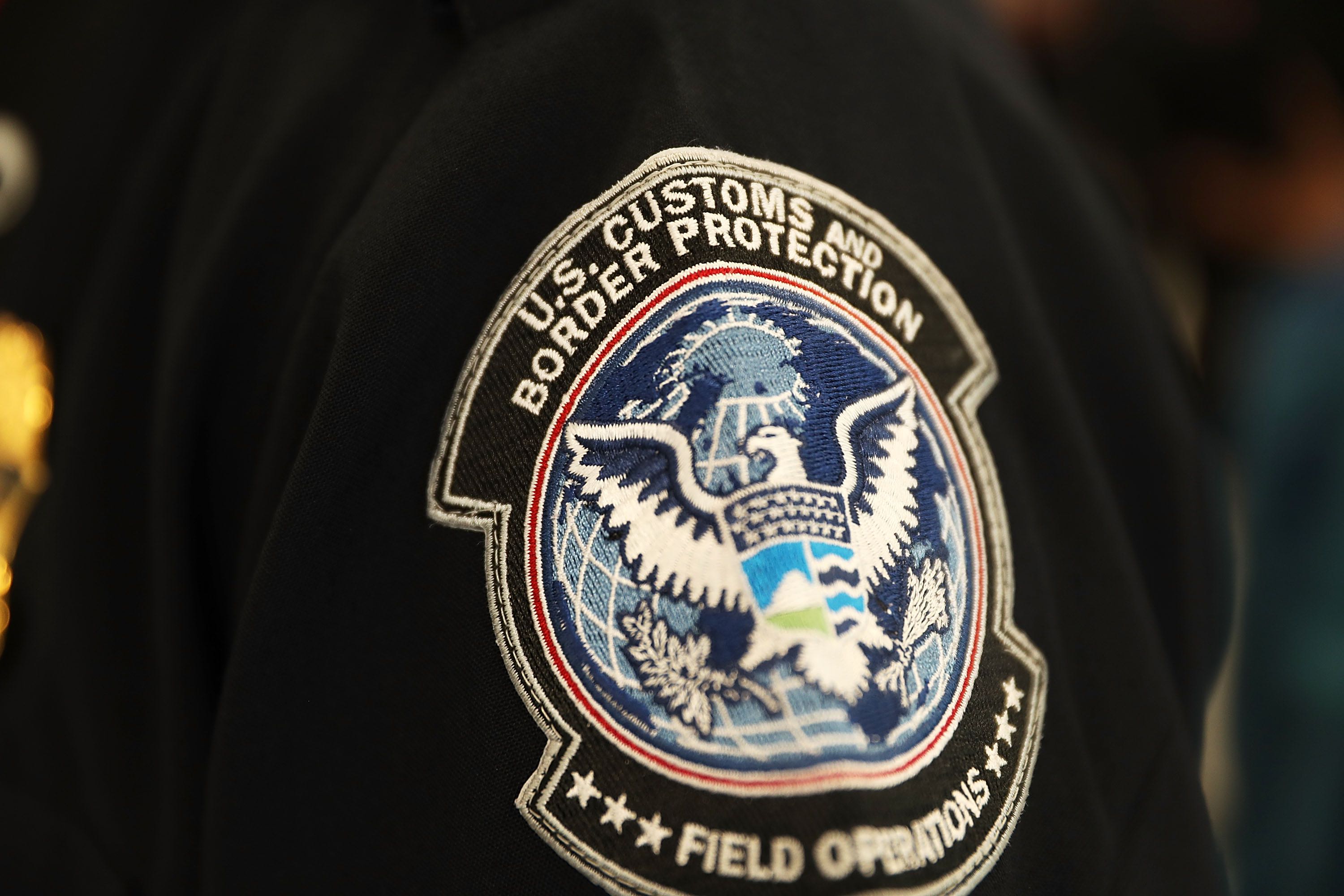 MIAMI, FL - 27 DE FEBRERO: Un parche en la manga de un oficial de Aduanas y Protección de Fronteras de U.S. que usa tecnología de reconocimiento facial en el Aeropuerto Internacional de Miami para examinar a un viajero. (Foto de Joe Raedle/Getty Images)