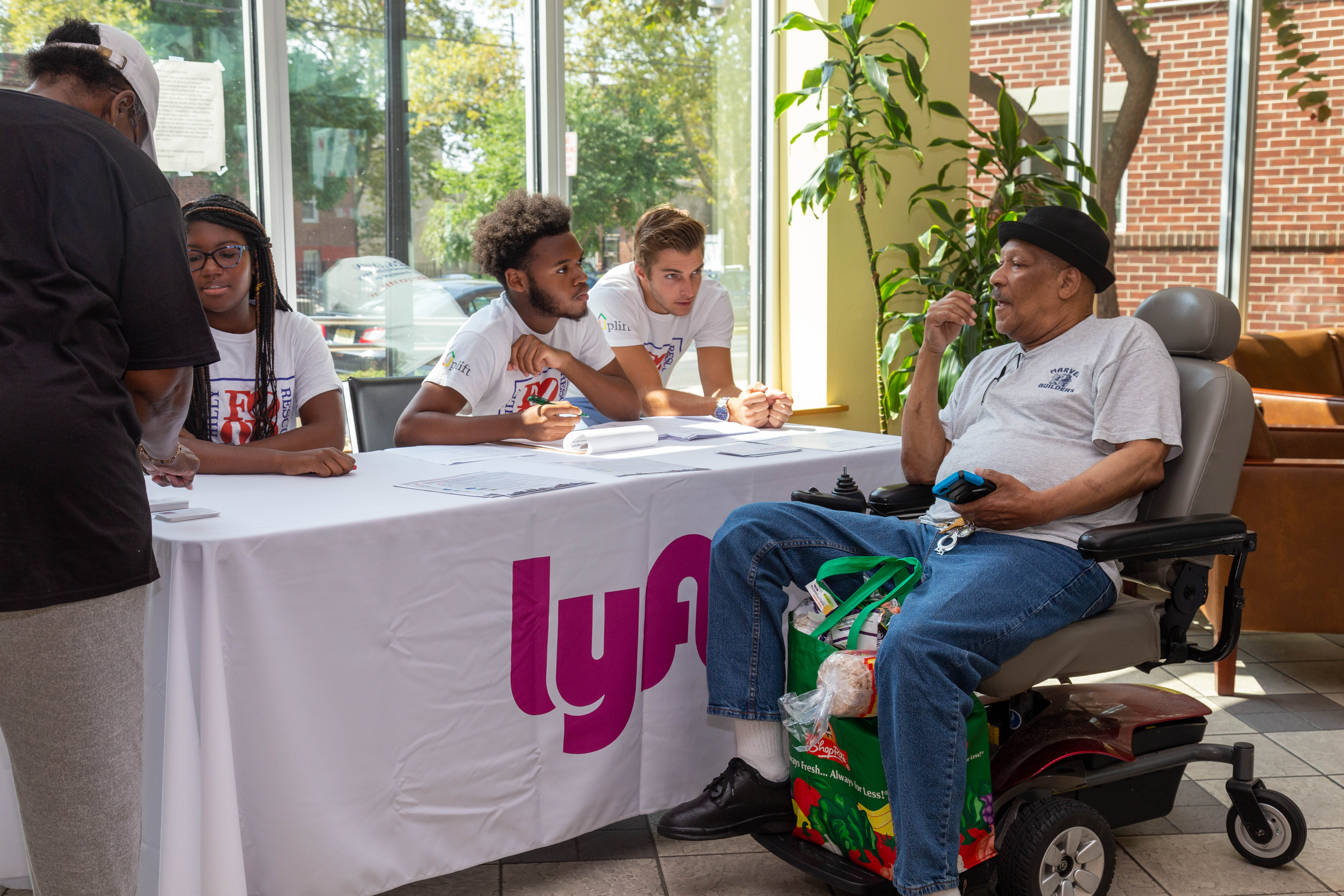 A resident of Nellie Reynolds Gardens, a PHA development, speaks with staffers from Lyft at the kickoff for the Grocery Access Program in Philadelphia. Photo Courtesy of PHA. 