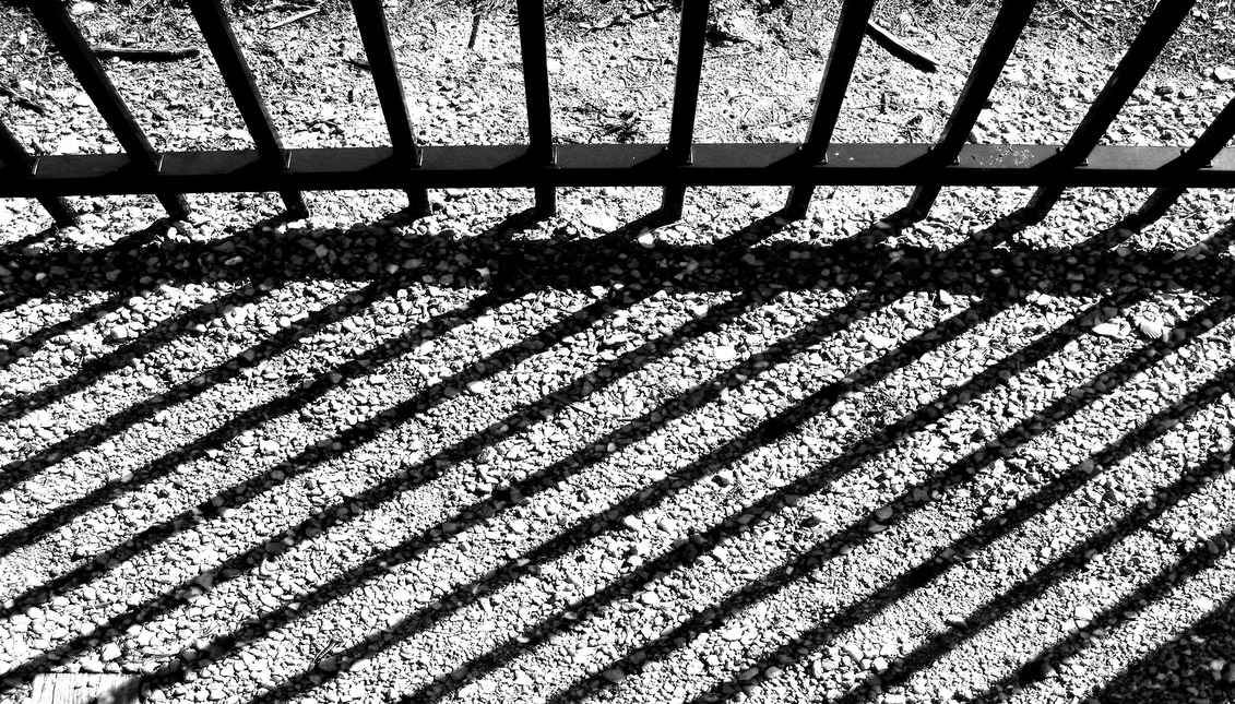 The shadow of some prison bars is reflected on the ground