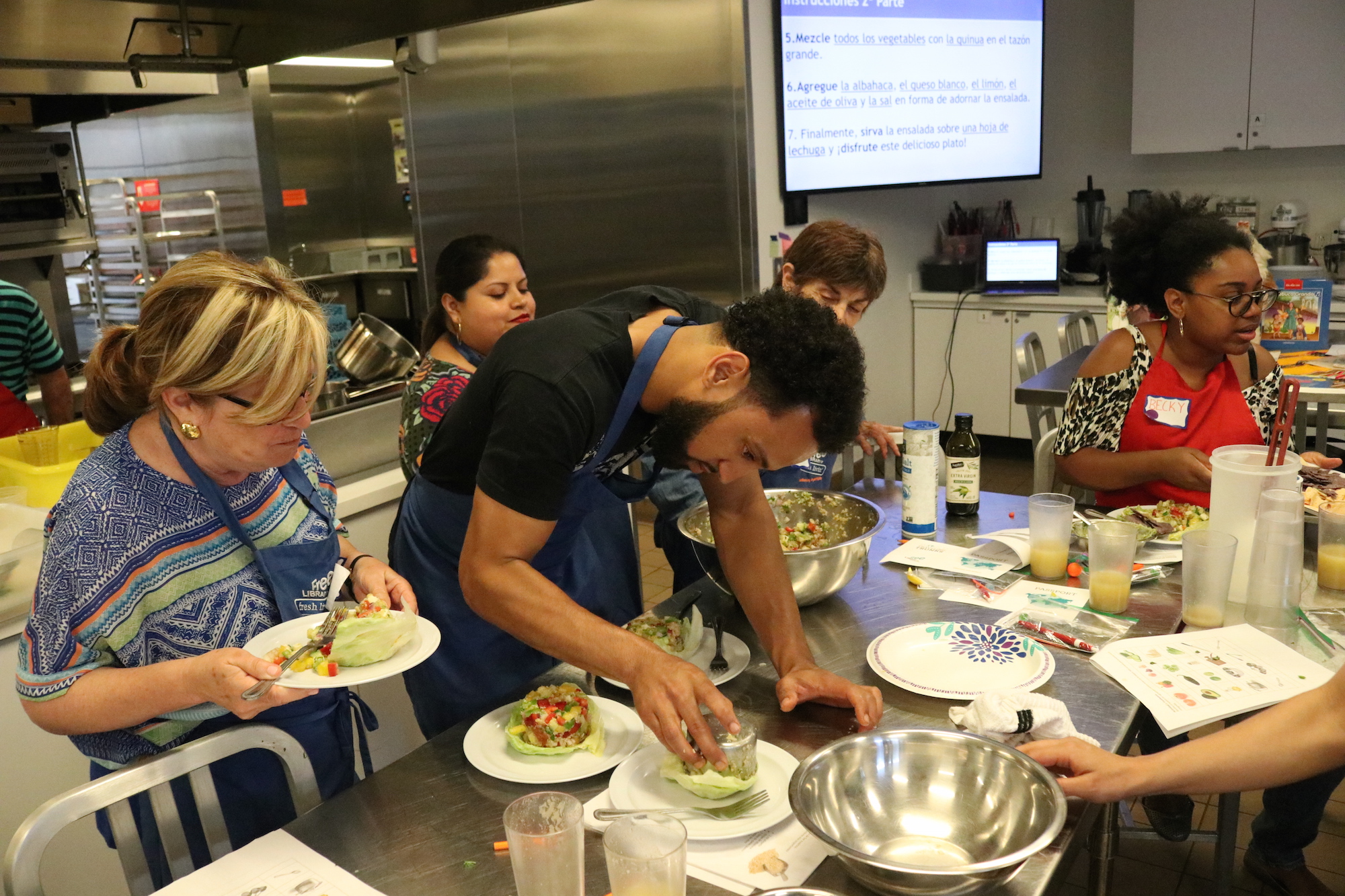 Participants in the Edible Alphabet en Español pack their quinoa salad into a cup before putting it over a bed of lettuce on Thursday, June 20, 2019. Photo: Nigel Thompson/AL DÍA.