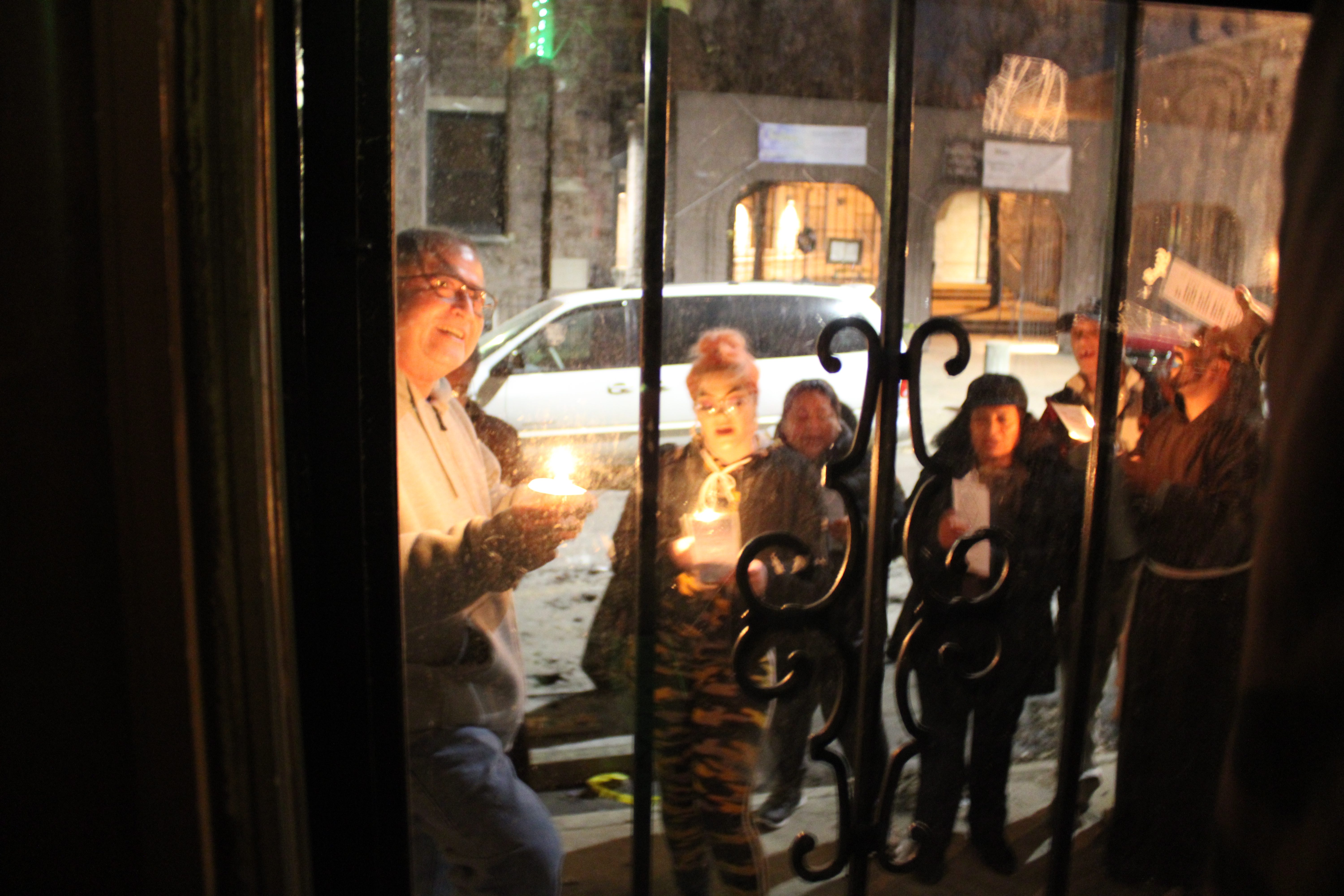 Marco Antonio Osuna (left) and other celebrants gather outside the door of Maria Isabel Sanchez's house, on Church Street. They sang the part of Mary and Joseph in the reenactment of their search for lodging in Bethlehem according to the Bible story, as celebrated in the Central American and Mexican tradition of the posadas. Photo: Emily Neil / AL DÍA News