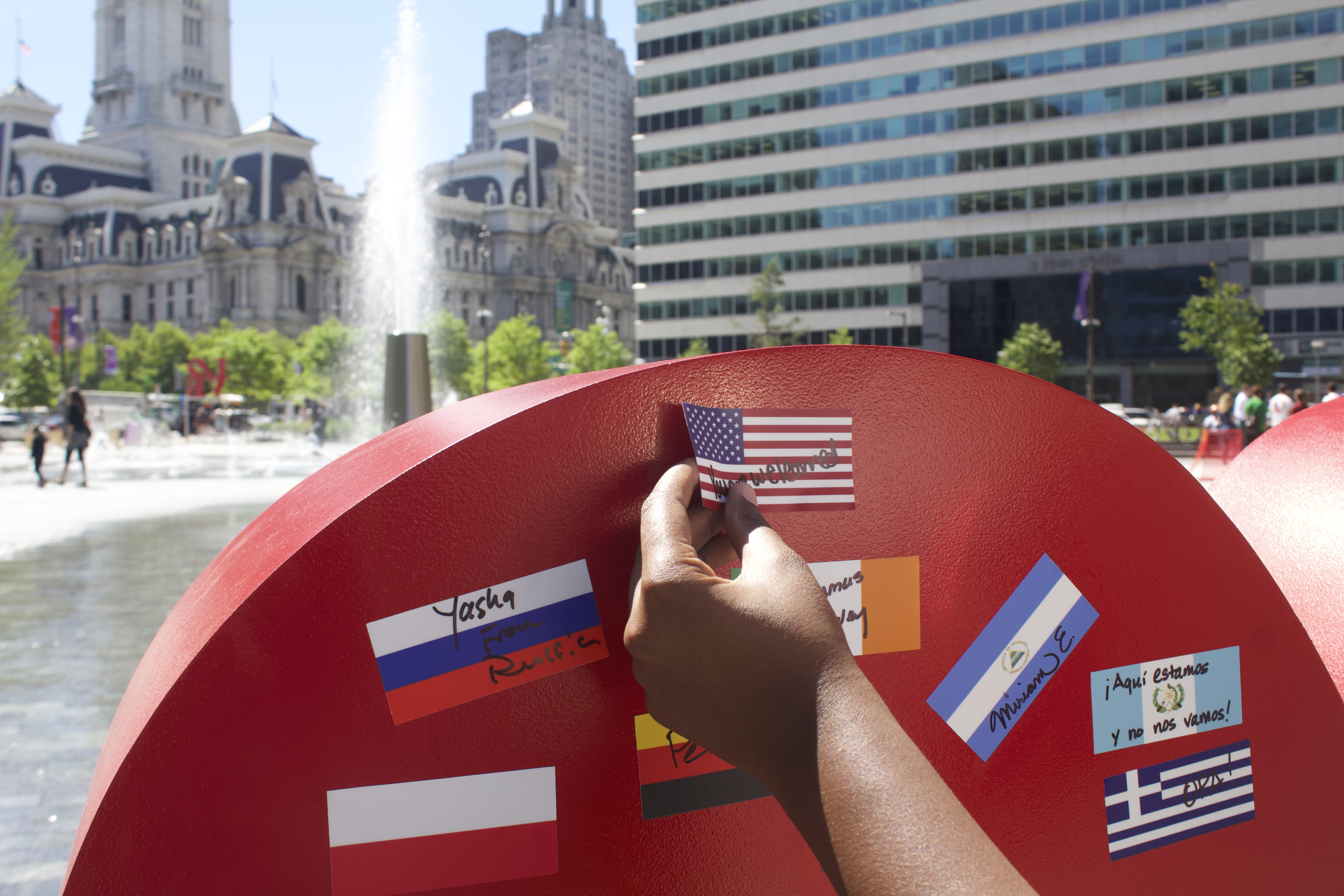 A participant at the Celebrate Immigrants event placed the flag of the United States with the phrase "You are Welcome" with flags from other countries on the art installation "I Love Philly" on June 4. 
Photo: Michelle Myers / AL DÍA News
