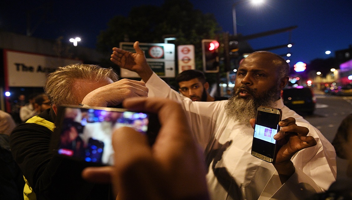 A man shows alleged pictures of the incident to onlookers near a police cordon near Finsbury Park, after a van collision incident in north London, Britain, 19 June 2017. EPA/FACUNDO ARRIZABALAGA