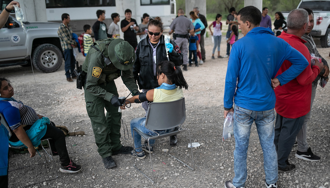 MCALLEN, TEXAS - JULY 02: A U.S. Border Patrol medic treats an immigrant for heat exhaustion after taking her into custody on July 02, 2019 in McAllen, Texas. The immigrants, mostly families from Central America, turned themselves into border agents after rafting across the Rio Grande from Mexico to seek political asylum in the United States. (Photo by John Moore/Getty Images)