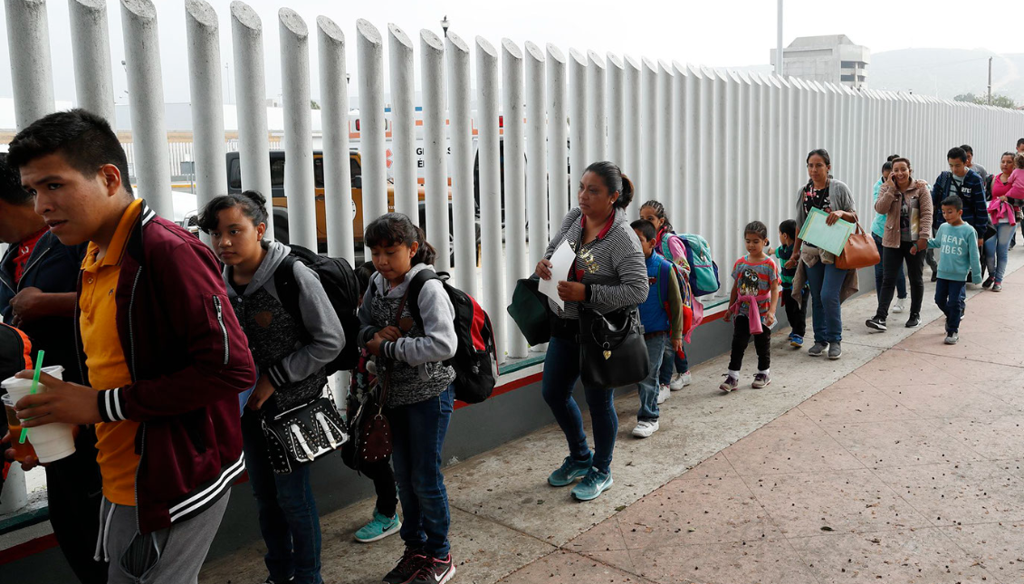 Personas haciendo cola para cruzar a Estados Unidos e iniciar el proceso de solicitud de asilo cerca del puerto de entrada de San Ysidro, en Tijuana (México). Fotografía: Gregory Bull/ AP News