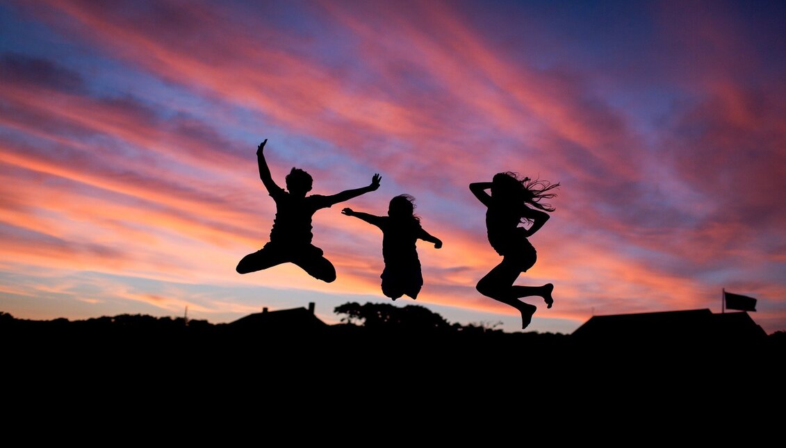 Happy jumping people at sunset. Image to illustrate note from the happiest country in the world