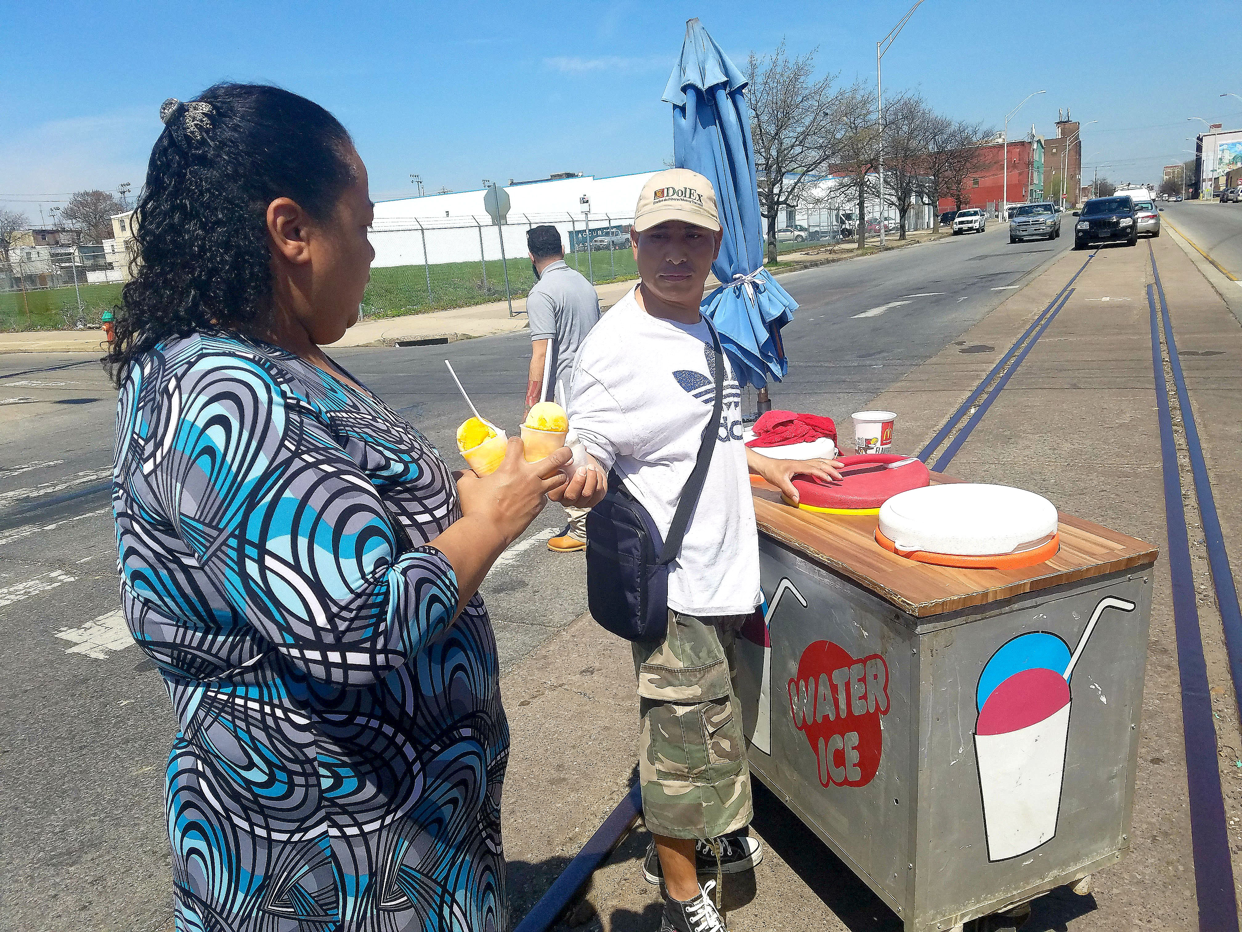 Juanita Pacheco gets a couple of piraguas from Gonzalo Ramirez along American Street.  Photo: Peter Fitzpatrick/AL DIA News 