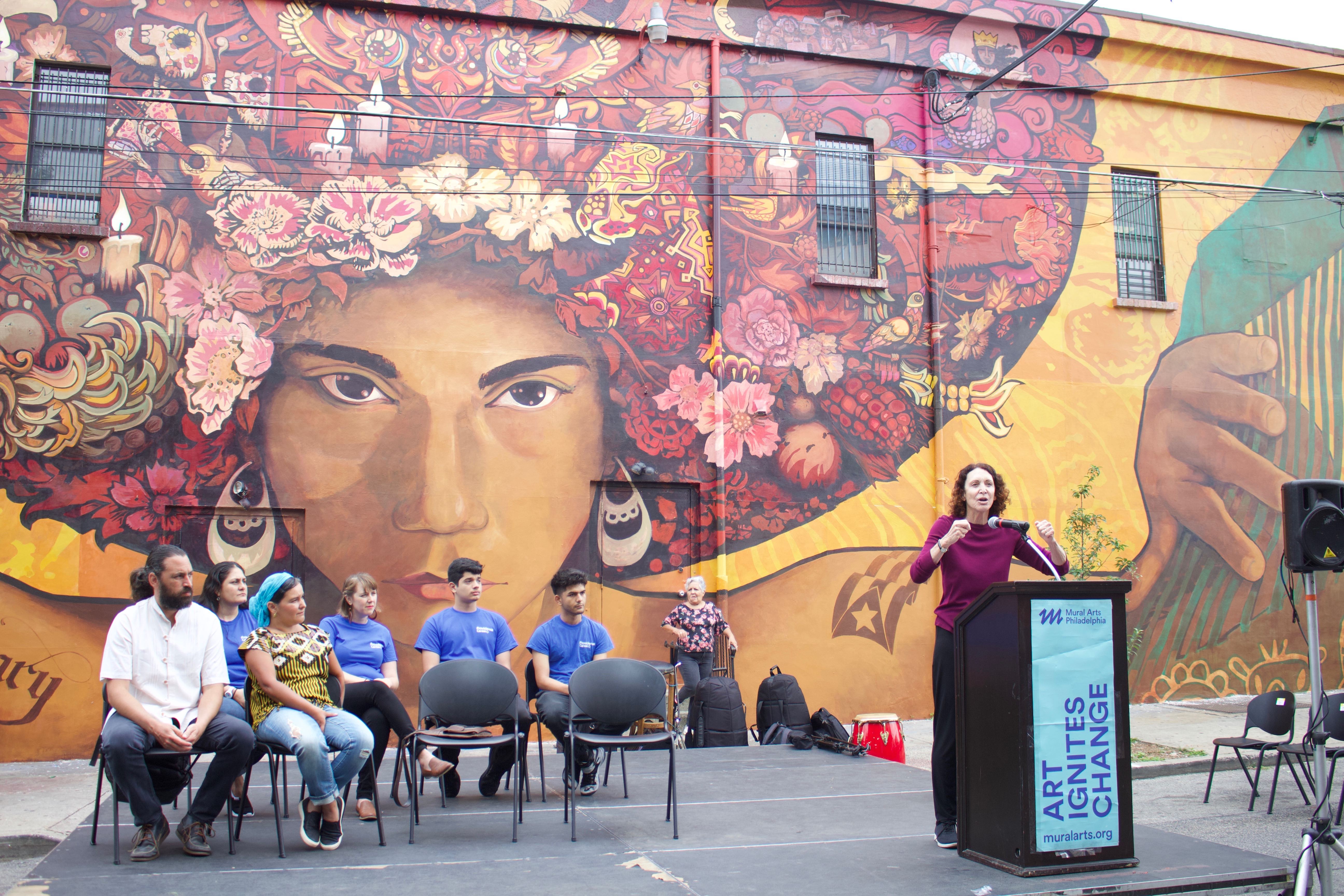 Jane Golden, executive director of Mural Arts Philadelphia, speaks at the dedication ceremony of the "Sanctuary City, Sanctuary Neighborhood" mural on the wall of the Providence Center at Fifth and Huntingdon streets in Fairhill. Photo: Emily Neil / AL DÍA News