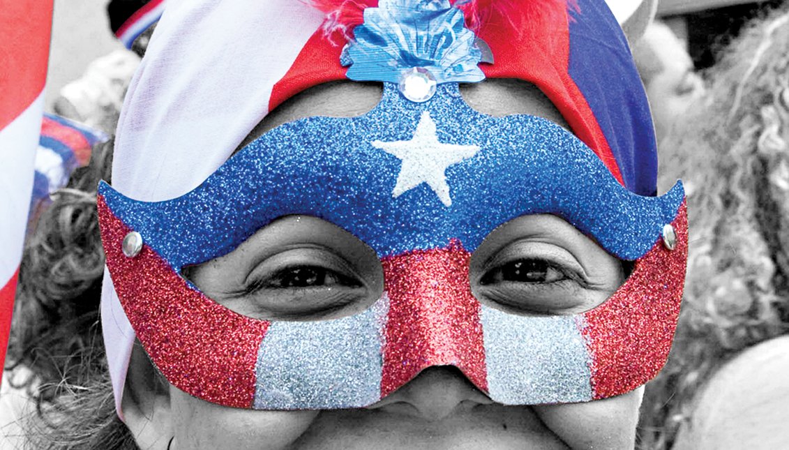 A woman wears the a mask with the Puerto Rican flag at the parade.
