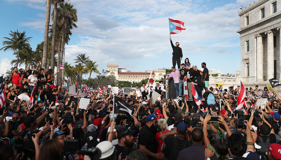 SAN JUAN, PUERTO RICO - JULY 17: Rapper Bad Bunny (holding flag) singer, Ricky Martin (black hat) and Rapper Residente (blue hat) join demonstrators protesting against Ricardo Rossello, the Governor of Puerto Rico July 17, 2019 in Old San Juan, Puerto Rico. Photo by Joe Raedle/Getty Images)