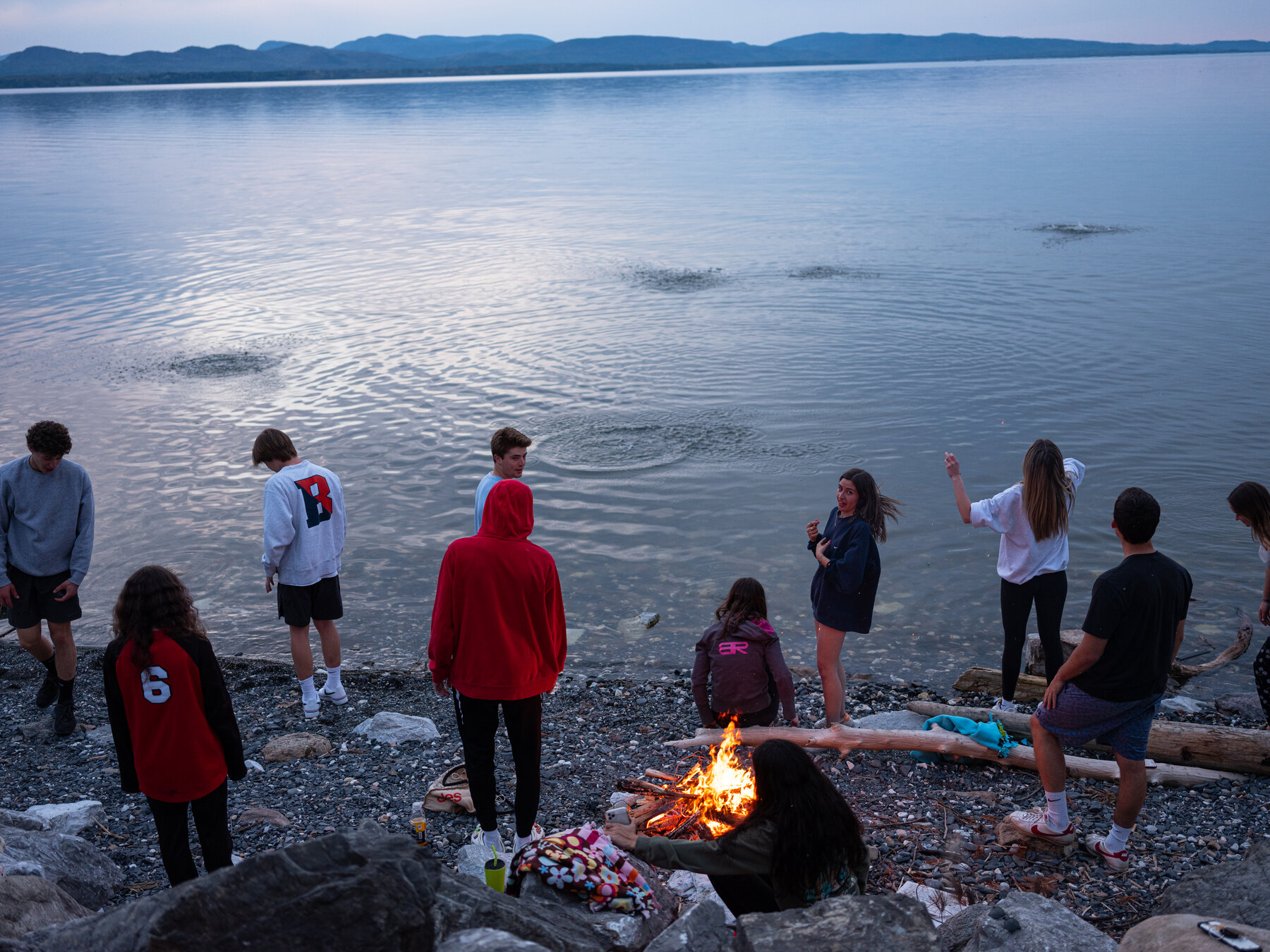 A group of teenagers skip stones across the water at sunset May 17, 2020 on Lake Champlain in Charlotte, Vermont. Photo: Robert Nickelsberg / Getty Images.