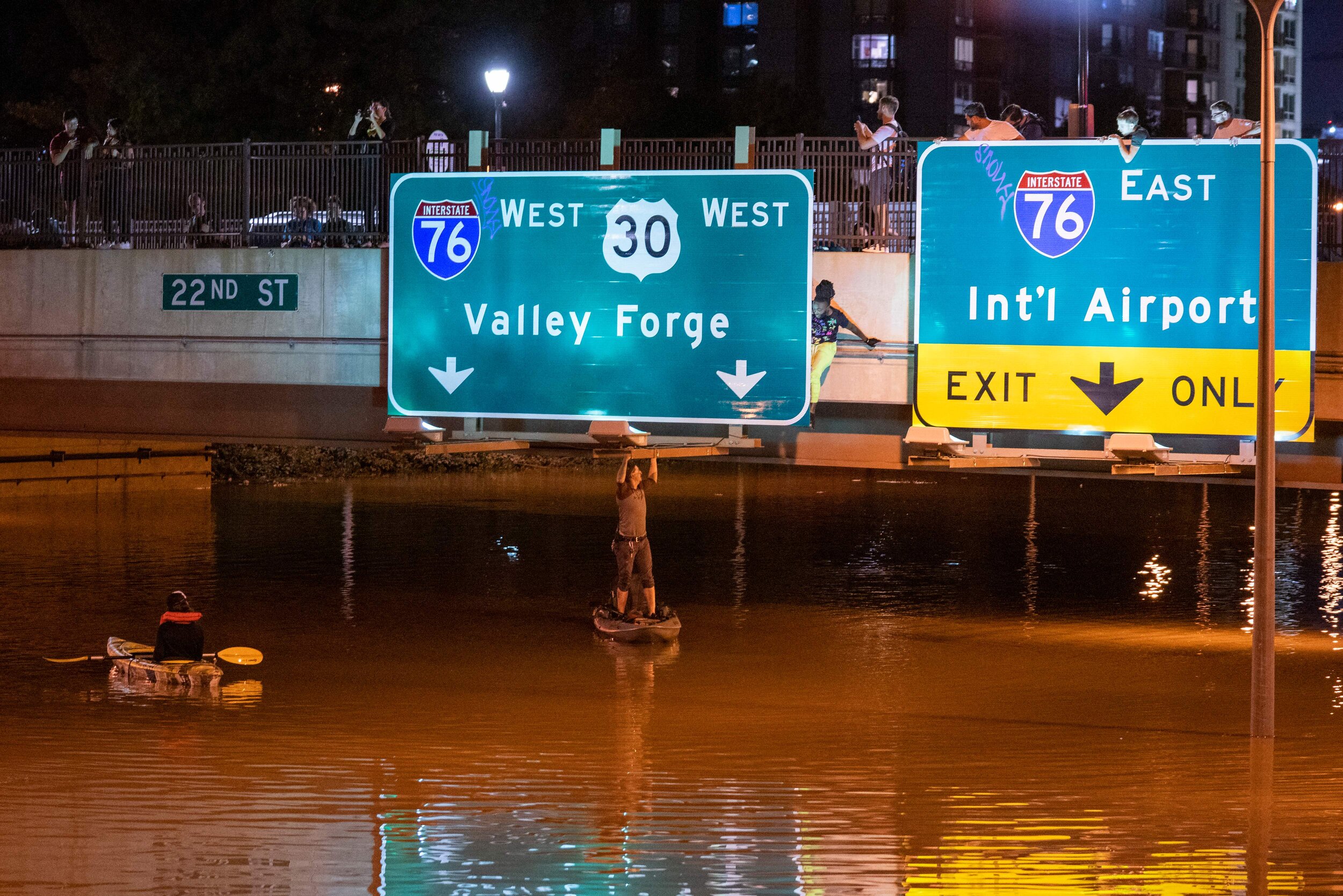 A kayaker poses for a photo under a highway sign when paddling down a portion of Interstate 676 after flooding from heavy rains from hurricane Ida in Philadelphia, Pennsylvania on September 2, 2021. Photo: Branden Eastwood/AFP via Getty Images.