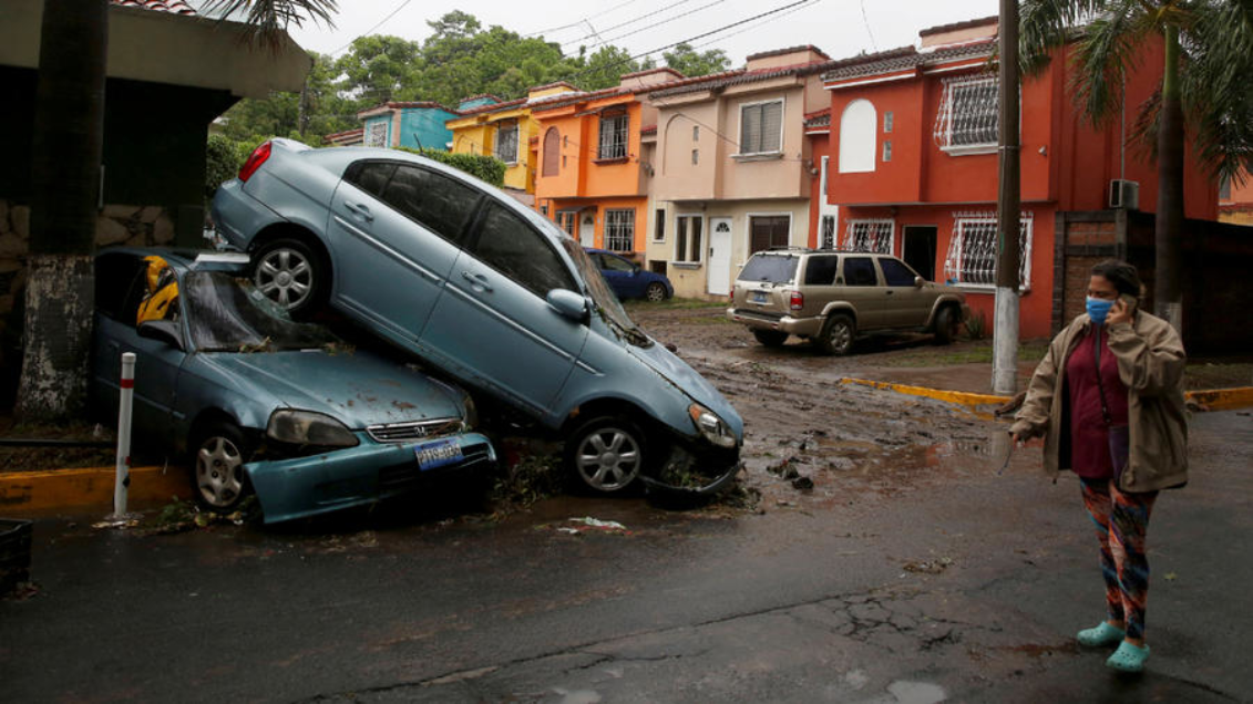 A woman walk in front of damaged cars during floods caused by Tropical Storm Amanda, in San Salvador, El Salvador May 31, 2020. © REUTERS/Jose Cabezas TPX