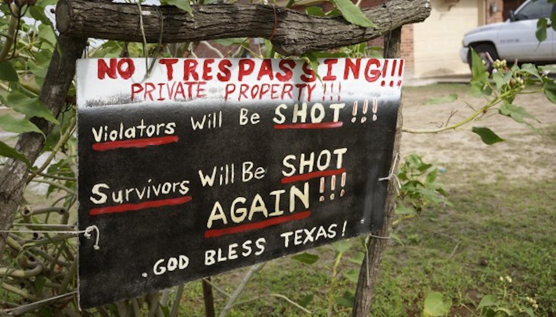 A handmade sign to deter trespassers hangs in the front yard of Fernando Rivera Jr.’s house in Brownsville, Texas, September 2, 2014. REUTERS/Rick Wilking