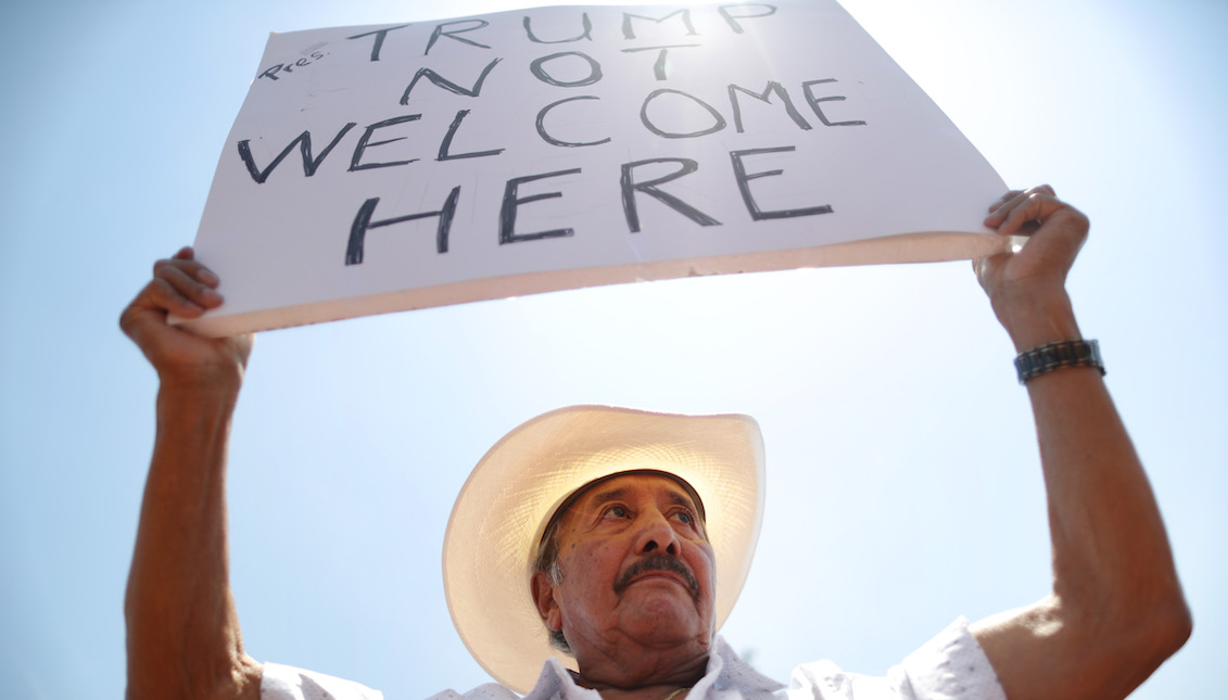 EL PASO, TEXAS - AUGUST 07: Miguel de Anda, born and raised in El Paso, holds a sign reading 'Trump Not Welcome Here' at a protest against President Trump's visit following a mass shooting, which left at least 22 people dead, on August 7, 2019, in El Paso, Texas. (Photo by Mario Tama/Getty Images)