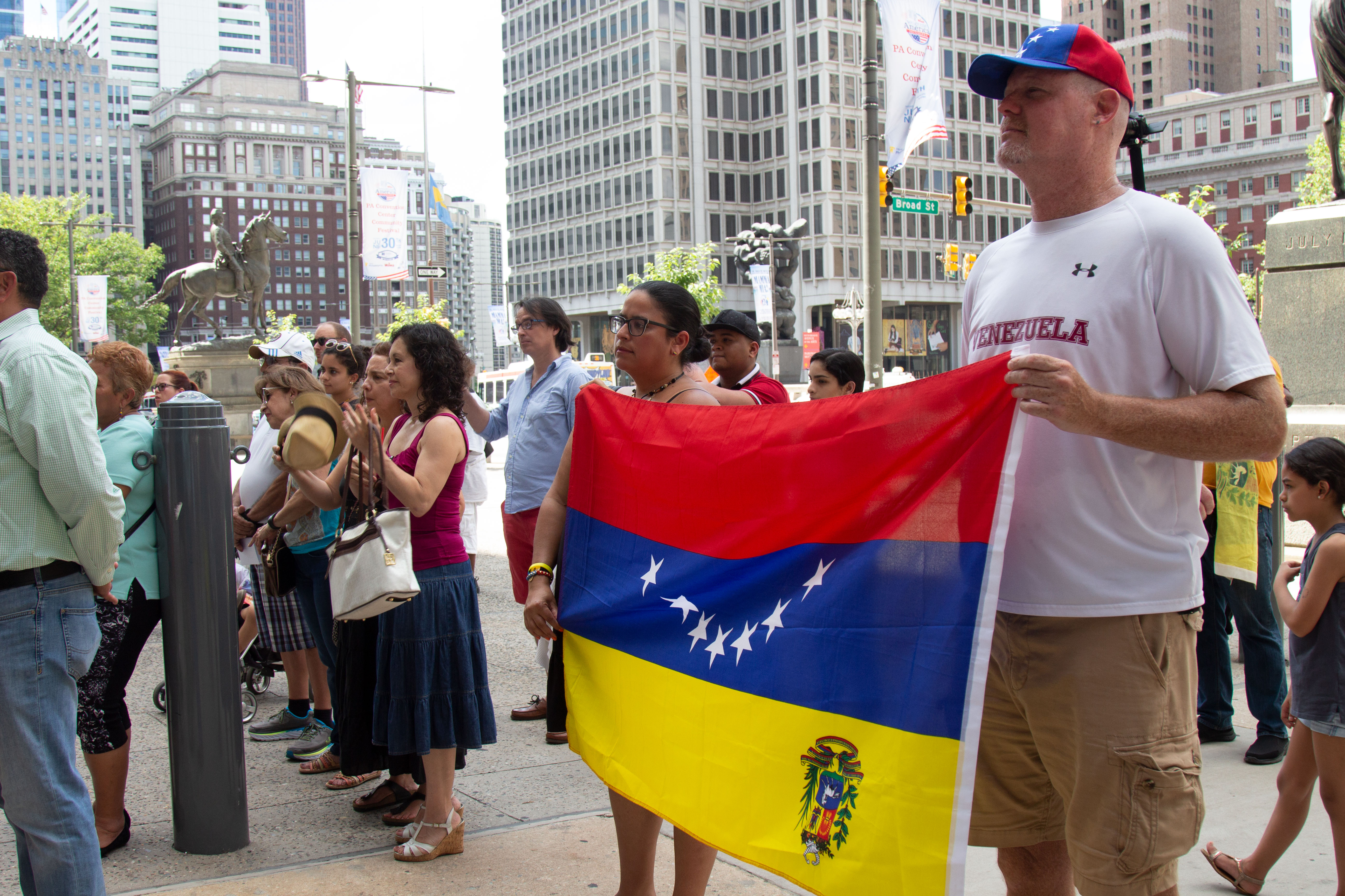 Members of Casa de Venezuela Myrteny Metzger (left) and Nicolas Di Giulo (right) raise the Venezuelan flag during an event at City Hall. Greta Anderson / AL DÍA News
