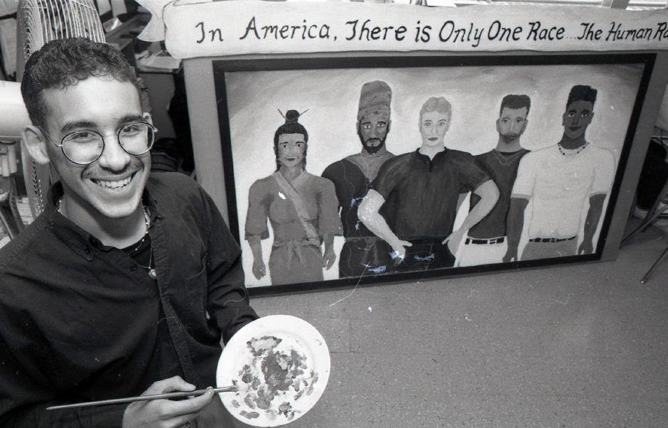 Miguel Cardona poses in front of the mural he worked on while a senior at Wilcox School. 