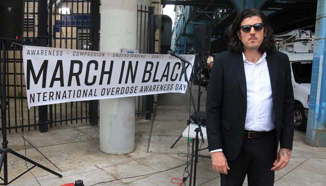 Dan Martino, 33, stands in front of the “March In Black” banner at York-Dauphin Station. This was the first of 4 stops on the march&#039;s mile long route through Kensington.